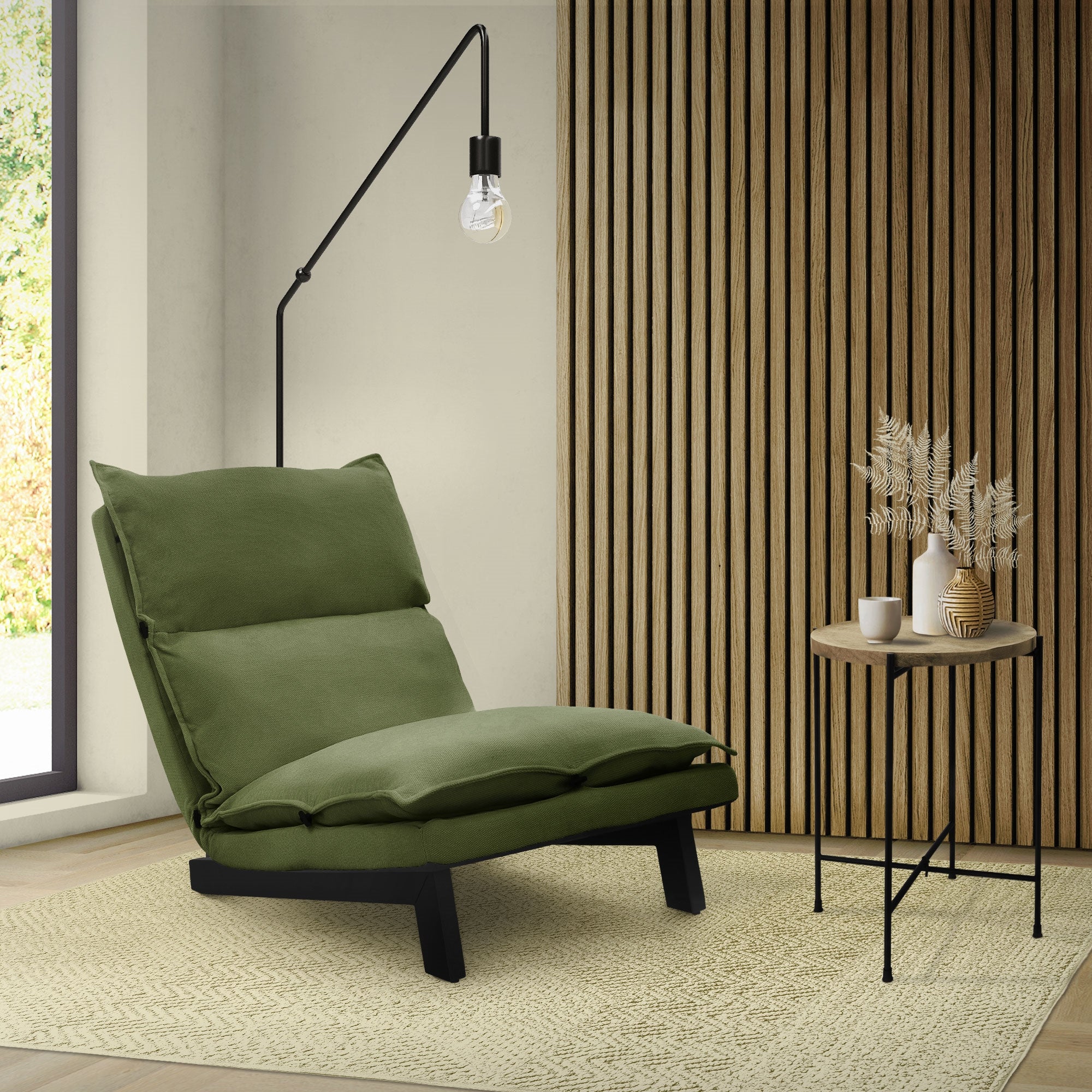 Un sillón verde está al lado de una mesa en una habitación luminosa.