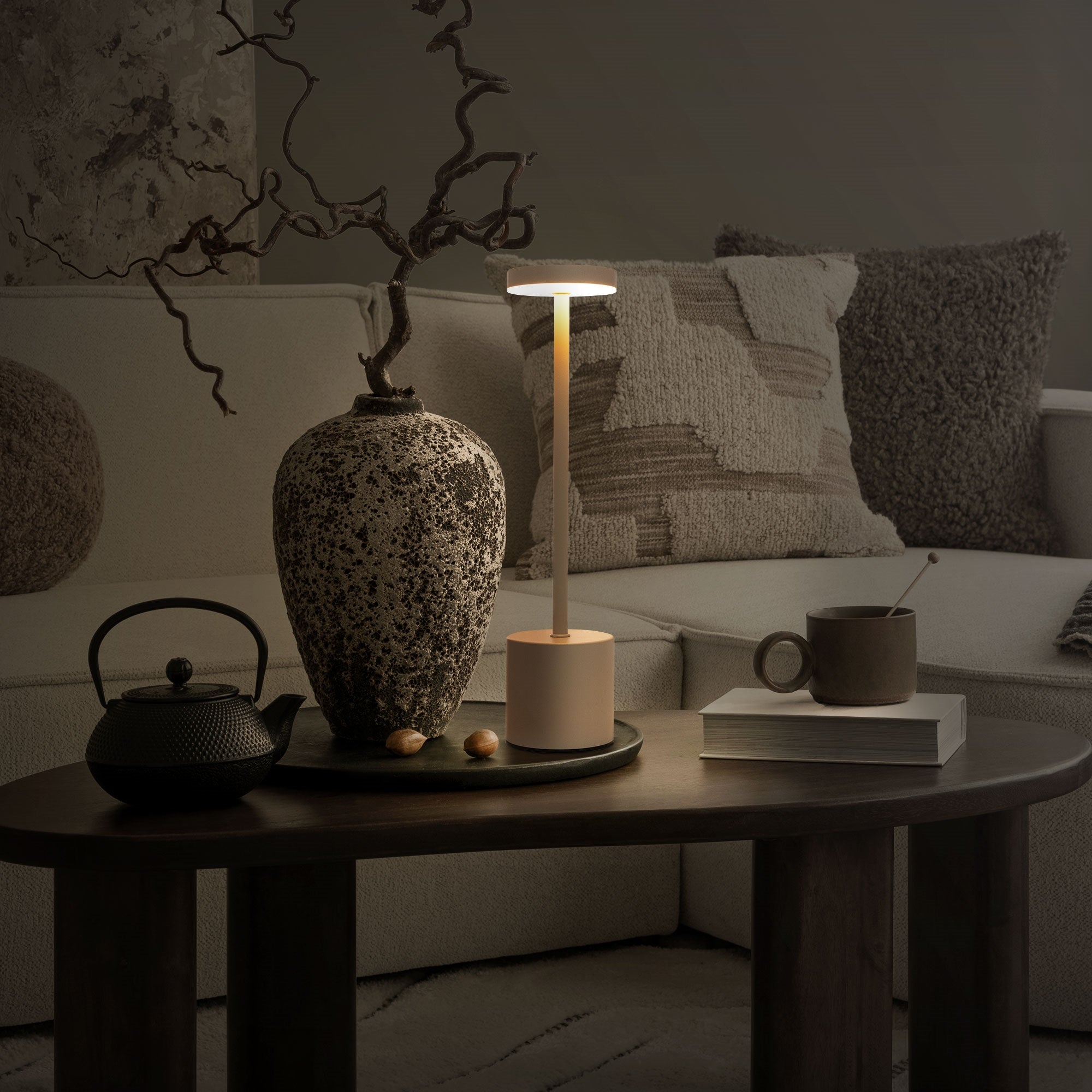 Lampe éclairée sur une table avec une théière et un vase.