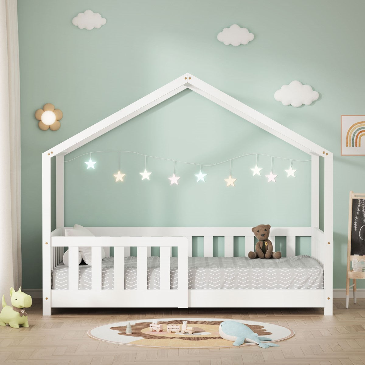 Lit cabane blanc avec protection antichute, guirlande lumineuse et ours en peluche devant un mur vert menthe décoré d'images de nuages.