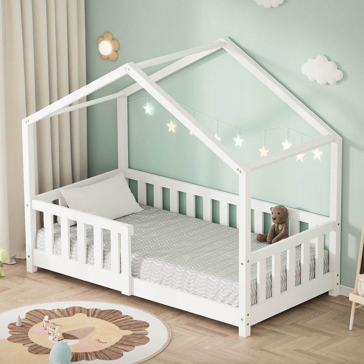 Ein Kinderbett in Hausform mit Sternenlichtern und einem Teddy auf der Matratze.
