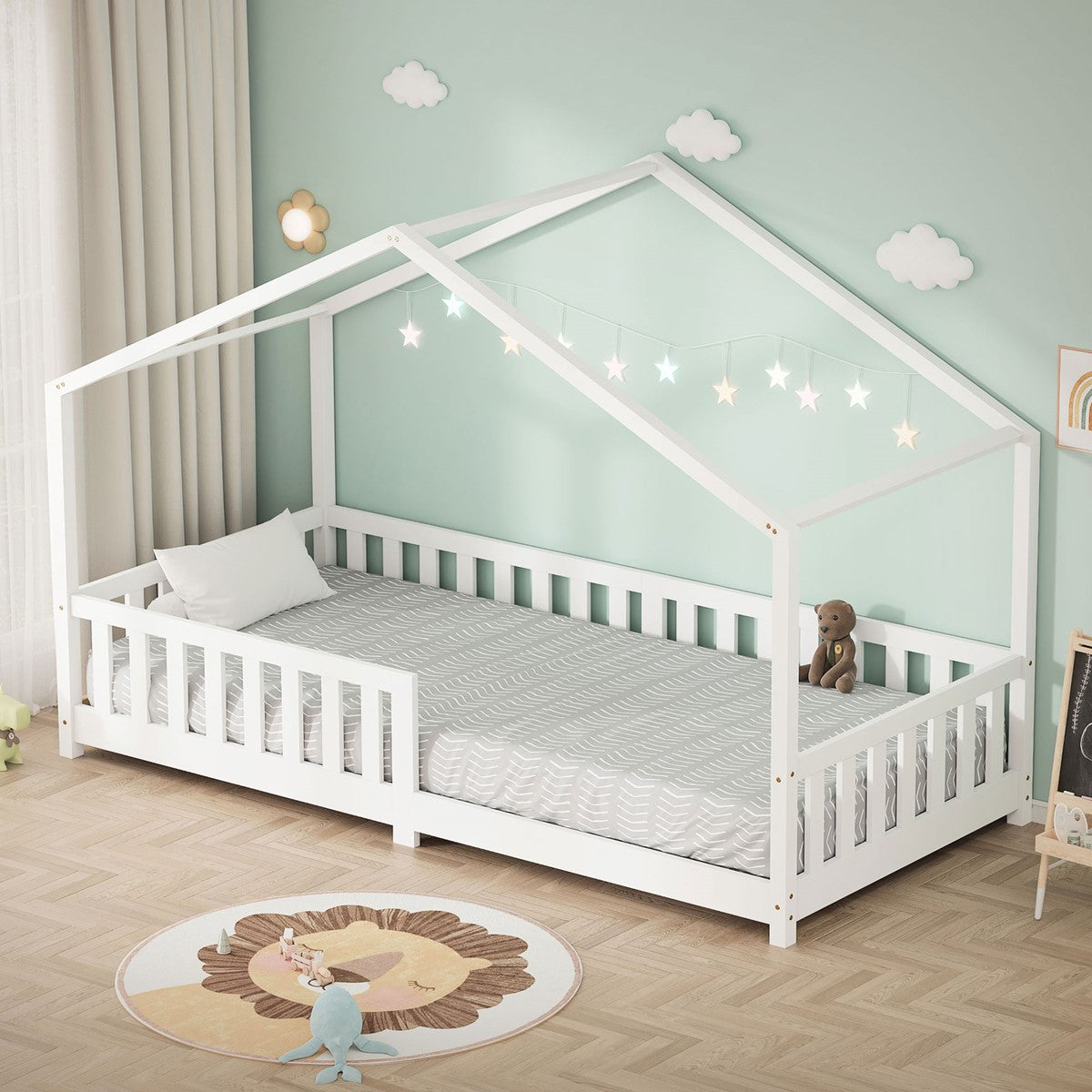White bed with a house-shaped roof, pillow and toy, against a wall with clouds.
