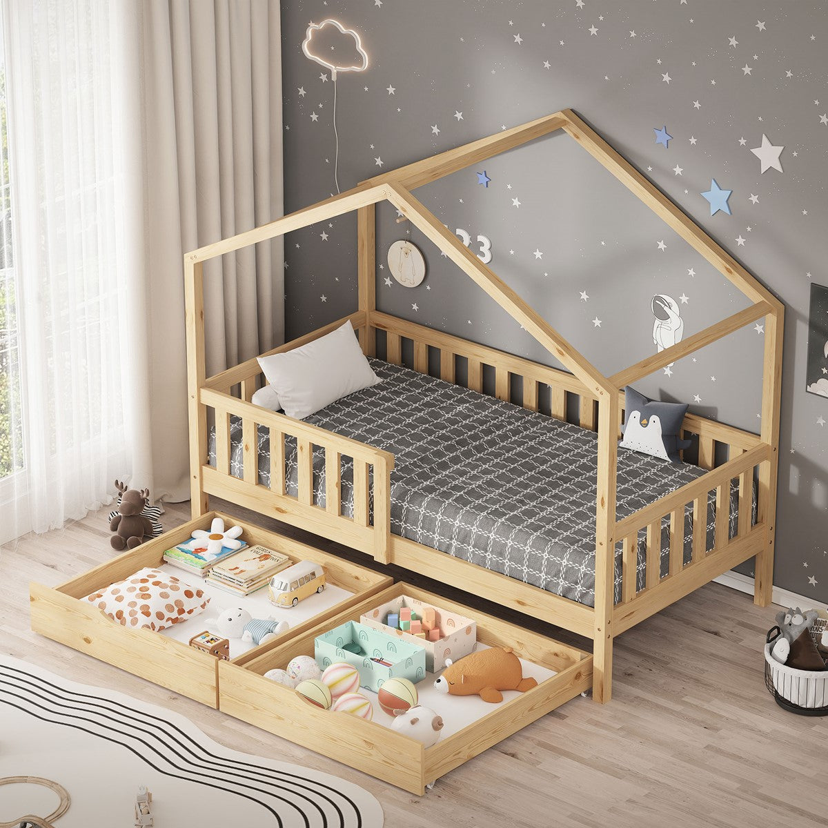 Natural-colored house bed with side rails and pulled-out drawers full of toys in front of gray star-patterned wallpaper.