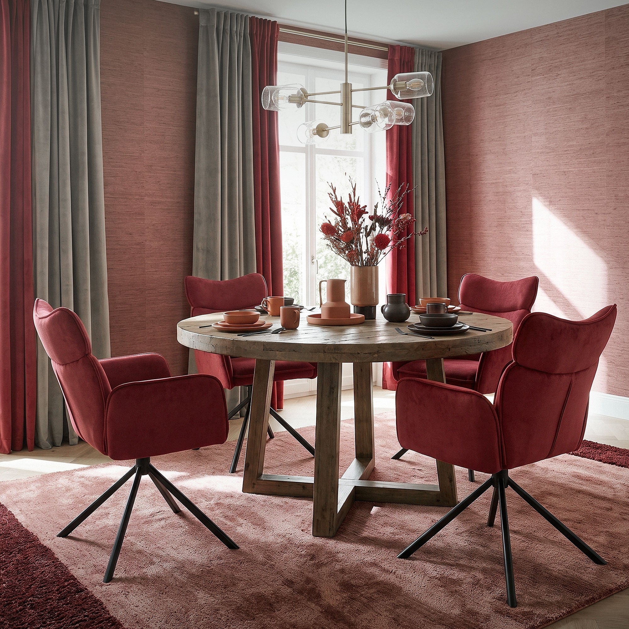 Table ronde avec des chaises rouges, décorée avec de la vaisselle et des fleurs.