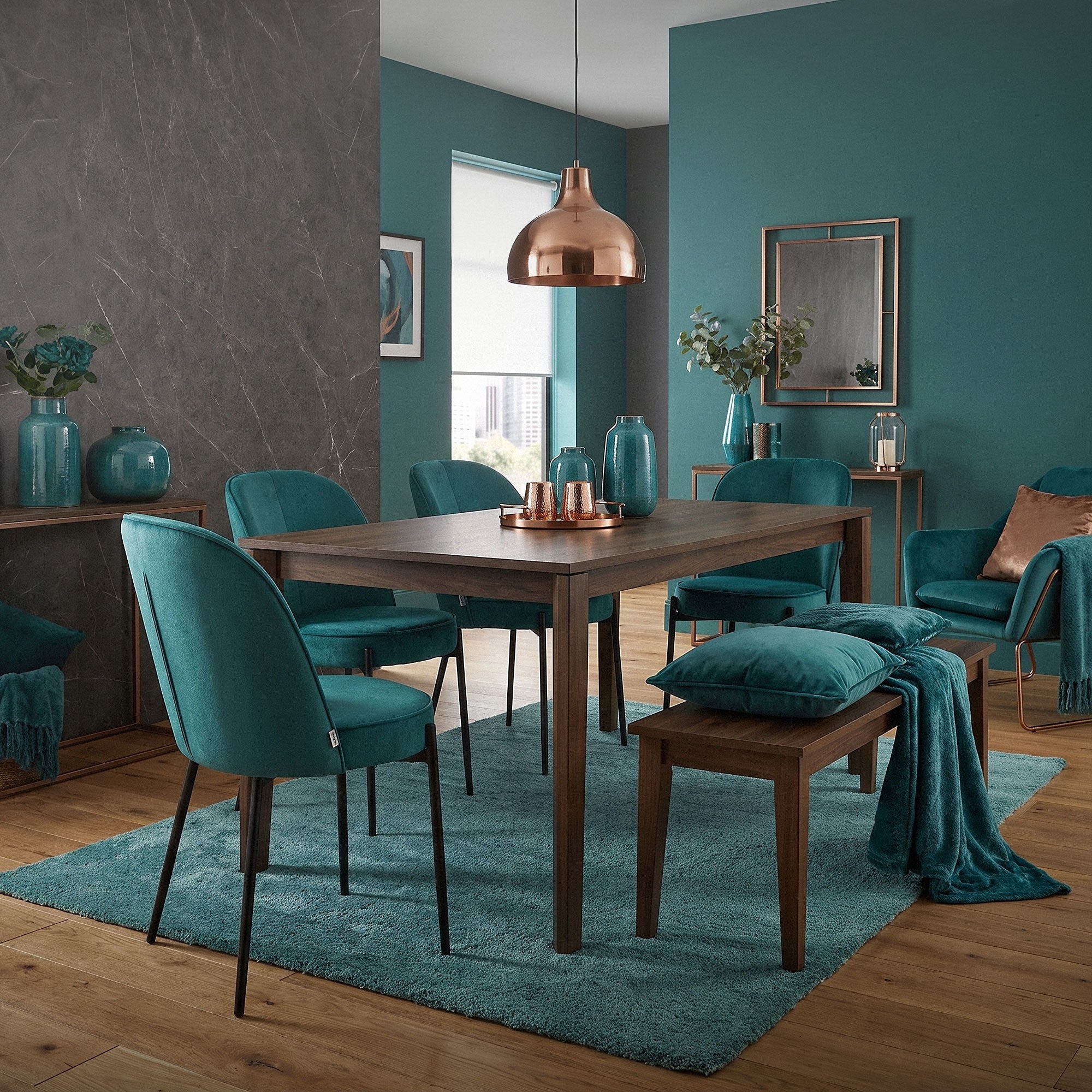 Sala da pranzo con sedie verdi, tavolo in legno e lampada a sospensione in rame.