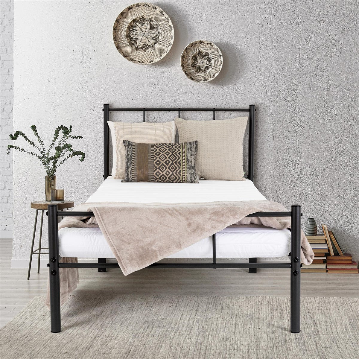 A bed with a black frame, decorated with pillows and a blanket.