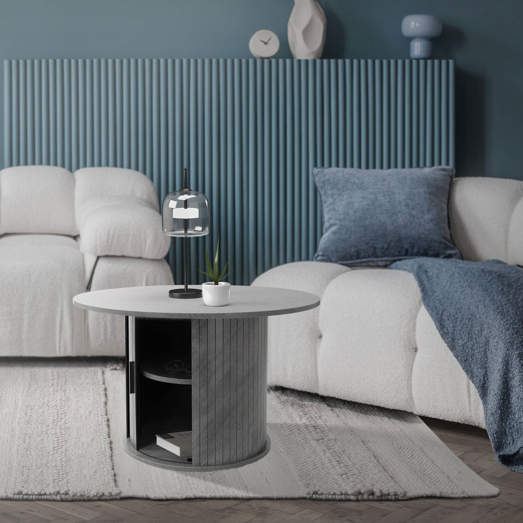 Ein runder Couchtisch mit einer Lampe und einer Pflanze in einem modernen Wohnzimmer.