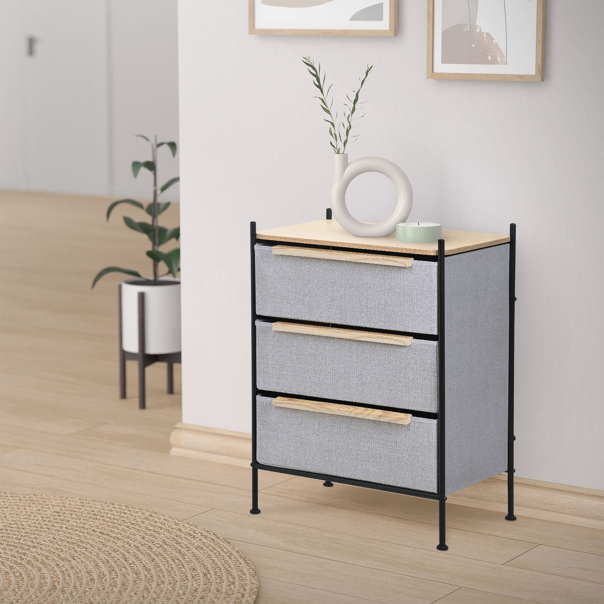 Drawer chest in a room, plants and picture frames in the background.