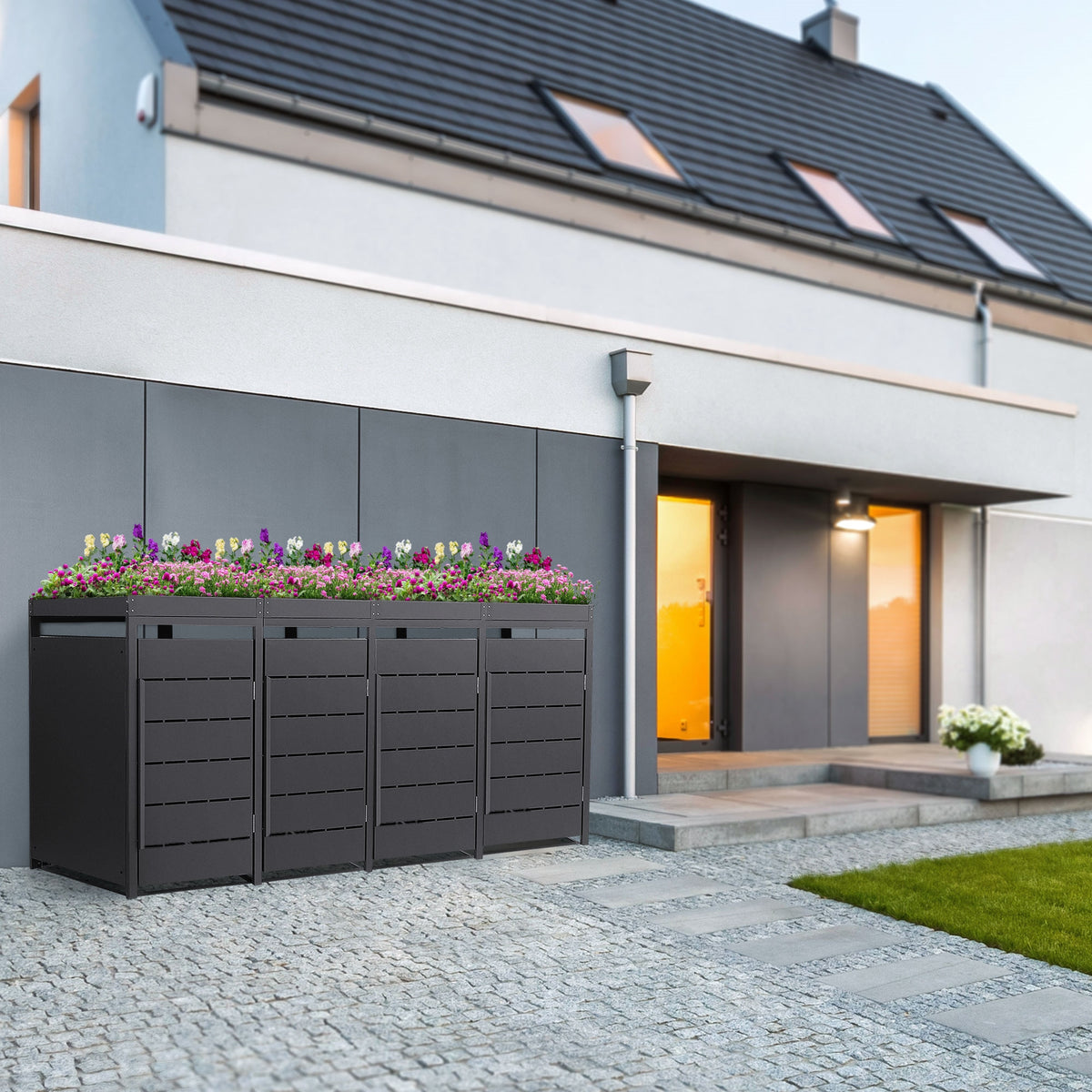 Drei Abfallbehälter mit Blumen auf einem modernen Hausvorplatz.