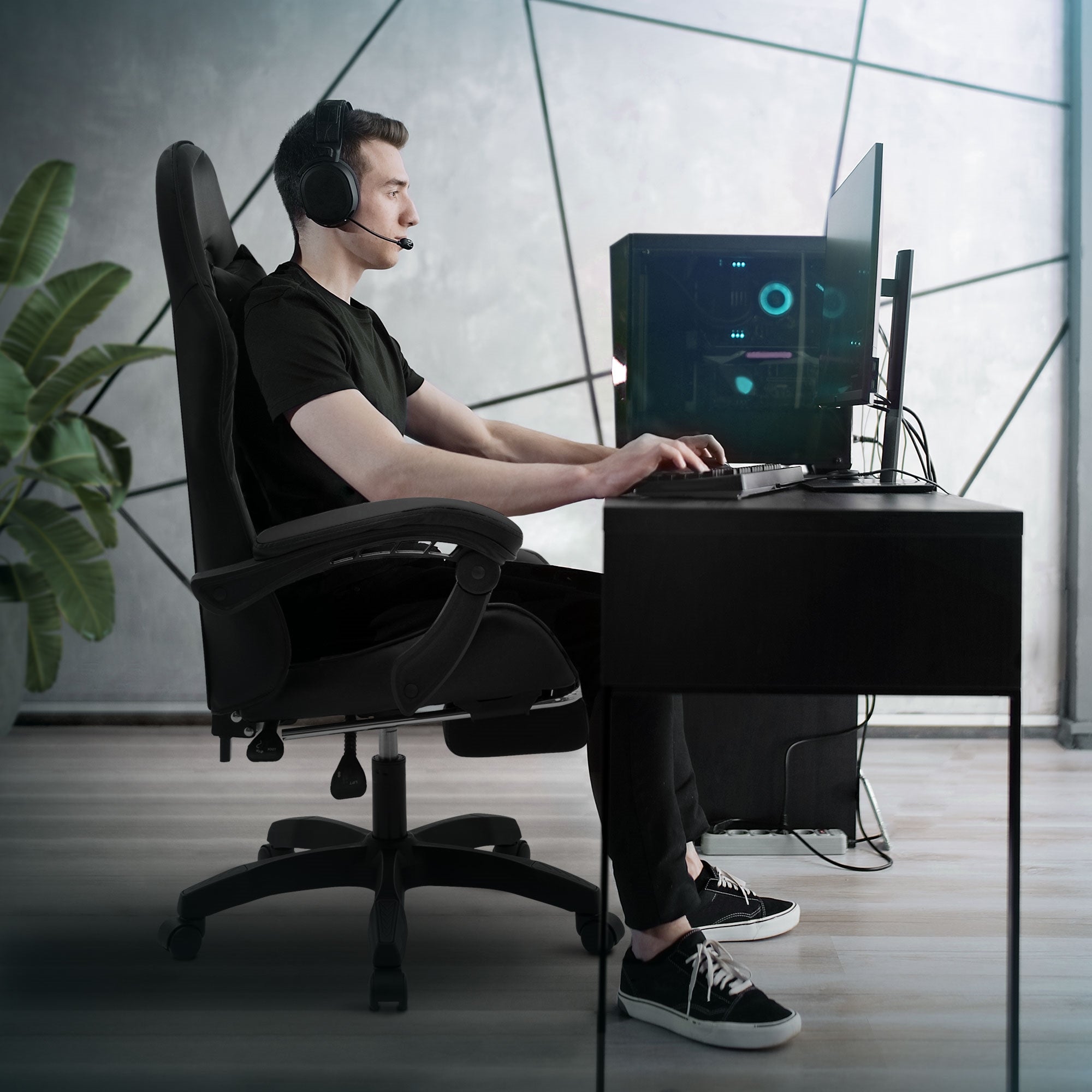 Mann sitzt an Schreibtisch, trägt Headset und nutzt Computer.