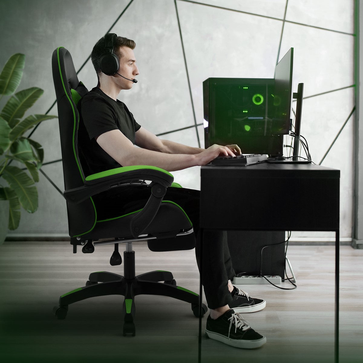 Junger Mann mit Headset sitzt an Schreibtisch und nutzt Gaming-PC.