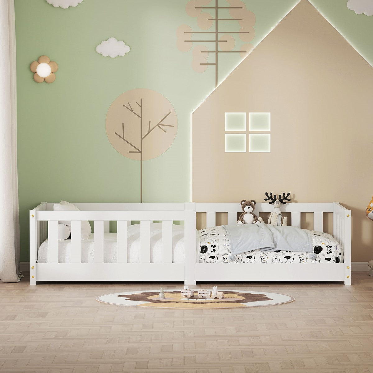 Wit kinderbed met spijlenzijkanten en beddengoed met een patroon, voor een groene muur met huis- en boomdecoraties.