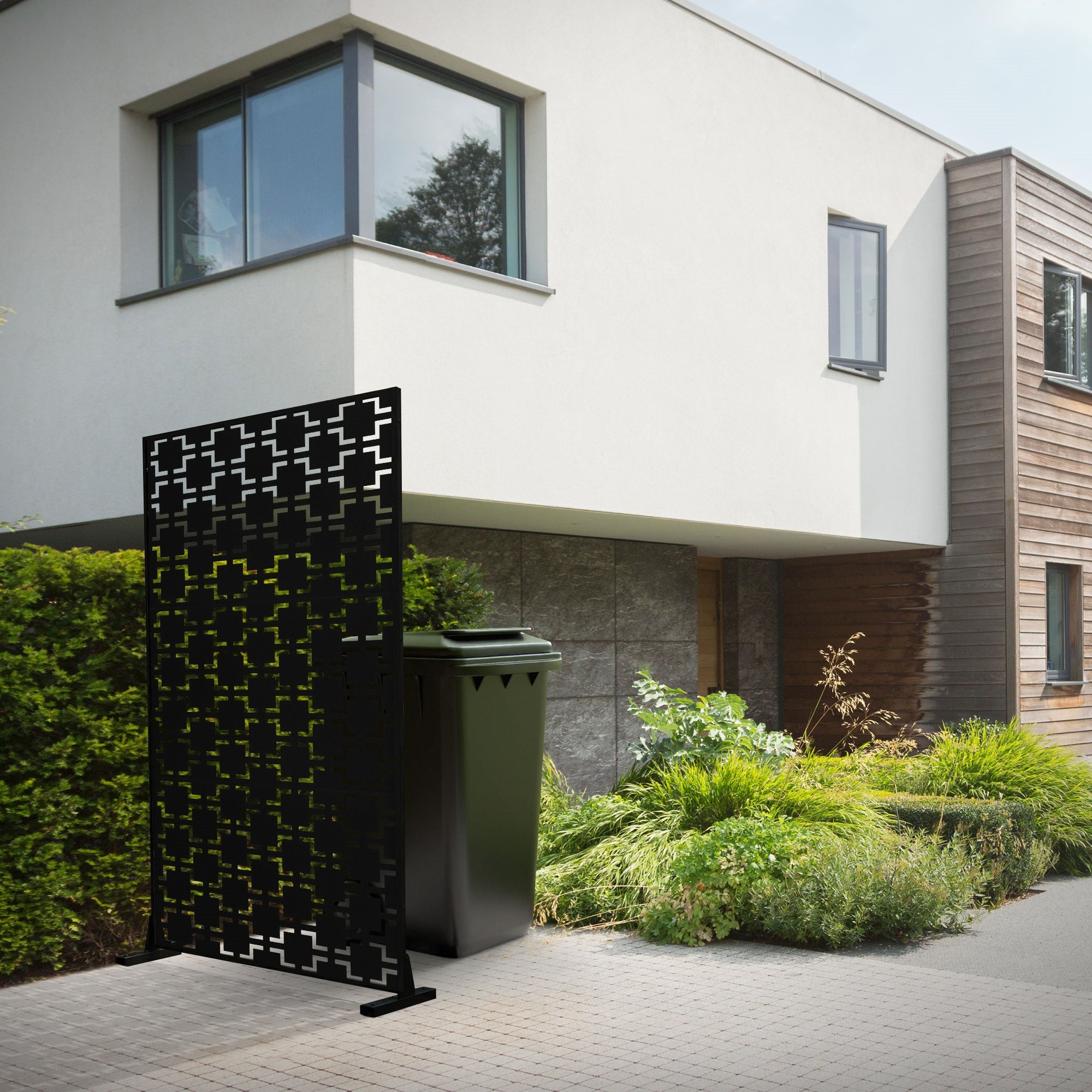 Modern house view with a privacy screen and a trash can in the foreground.