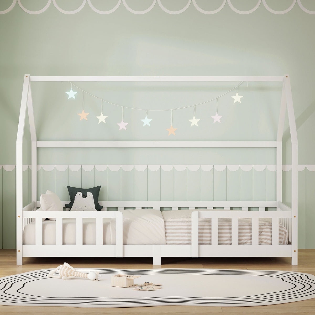 Lit d'enfant blanc avec lumières en forme d'étoiles et coussins dans une pièce lumineuse.