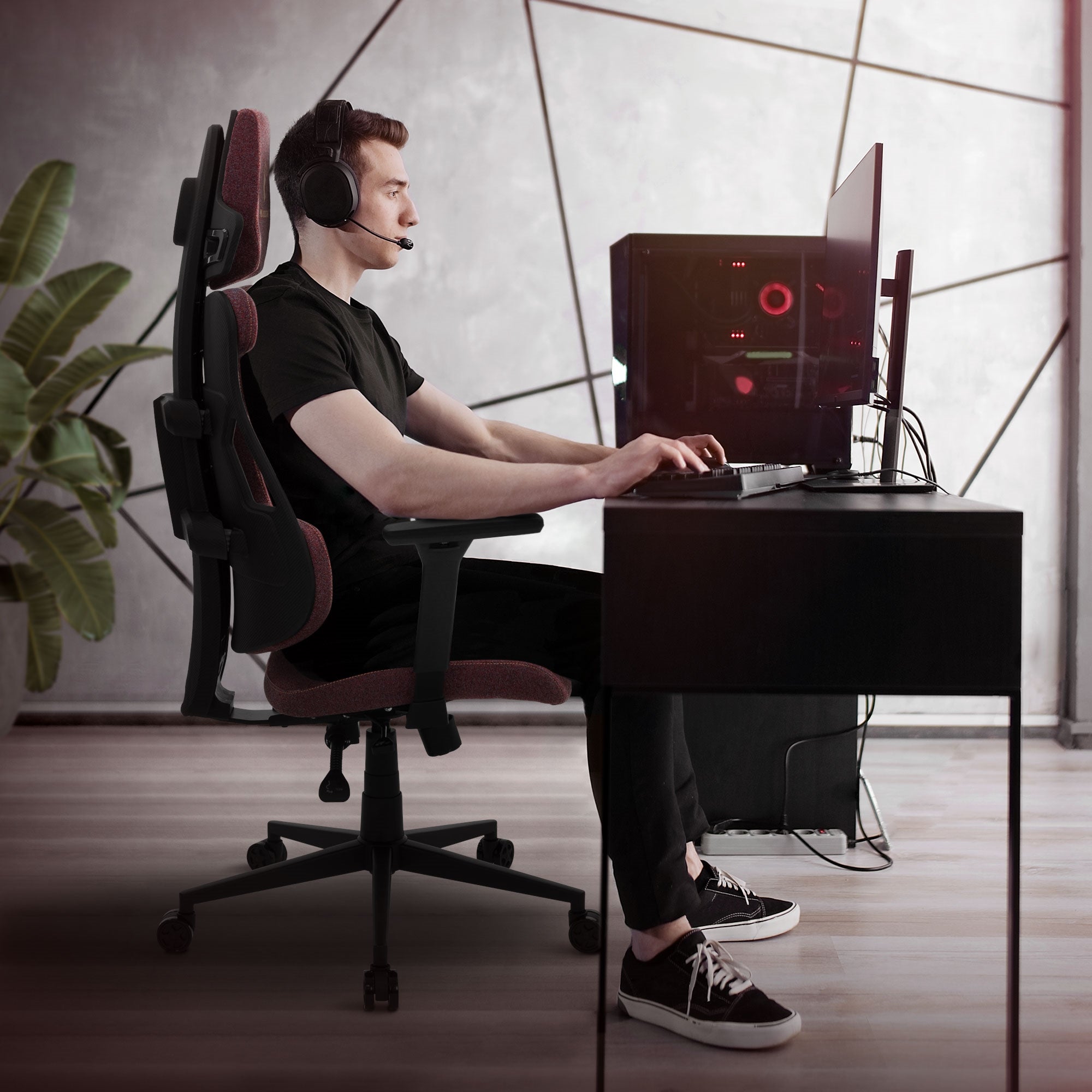Person mit Kopfhörern an einem Schreibtisch mit Gaming-PC.