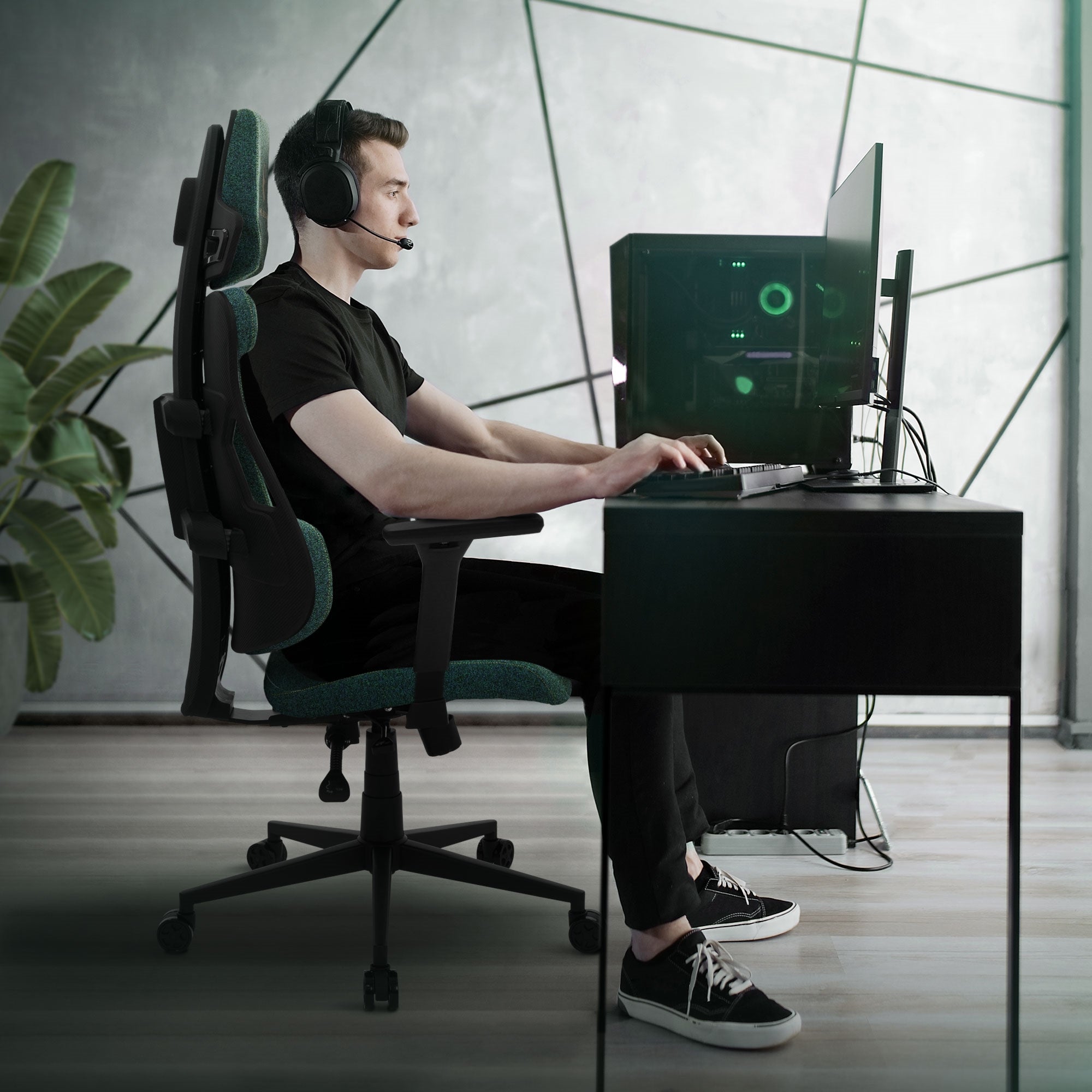 Mann sitzt an einem Schreibtisch in einem Gaming-Stuhl und trägt Kopfhörer.
