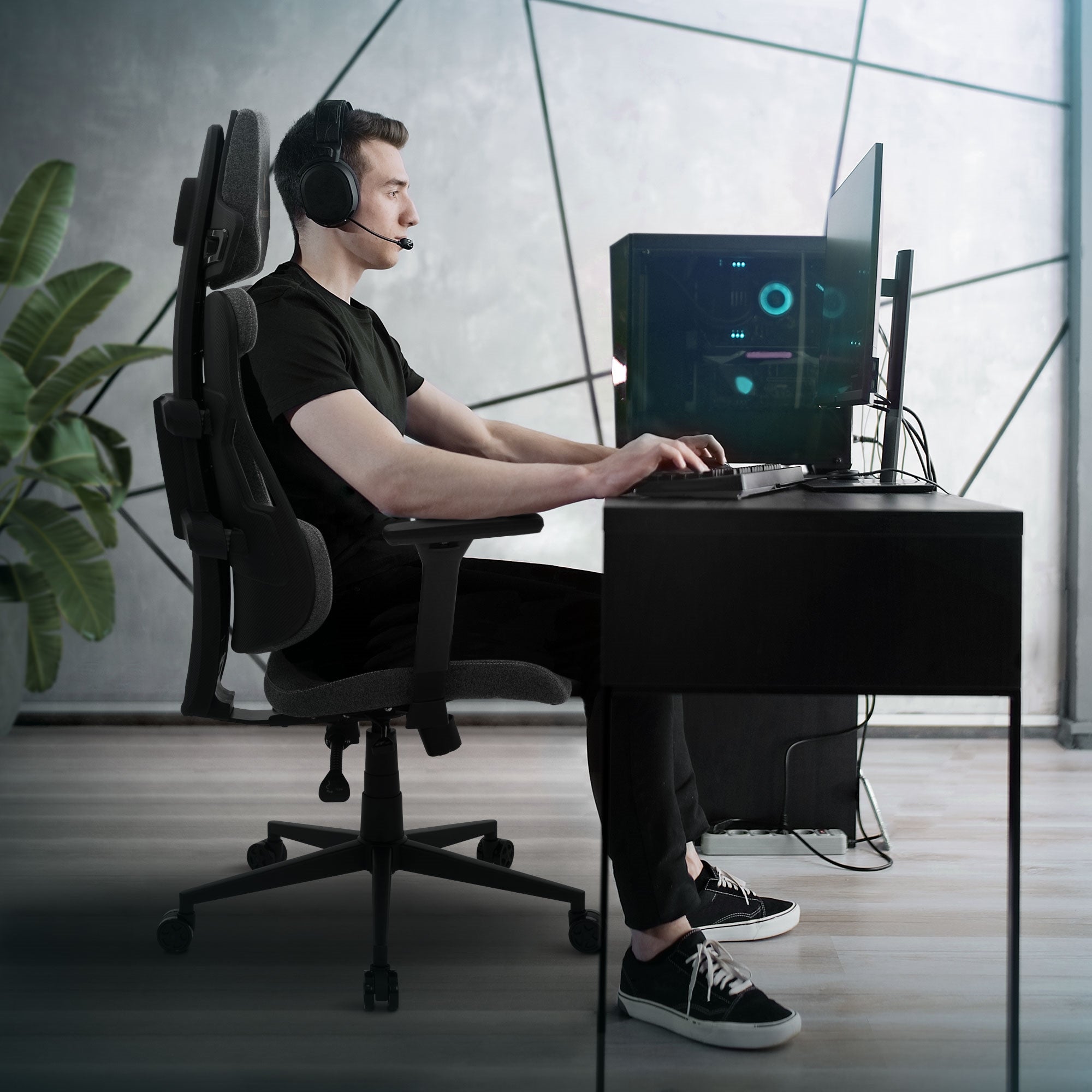 Ung mand sidder ved et skrivebord med computer og headset.