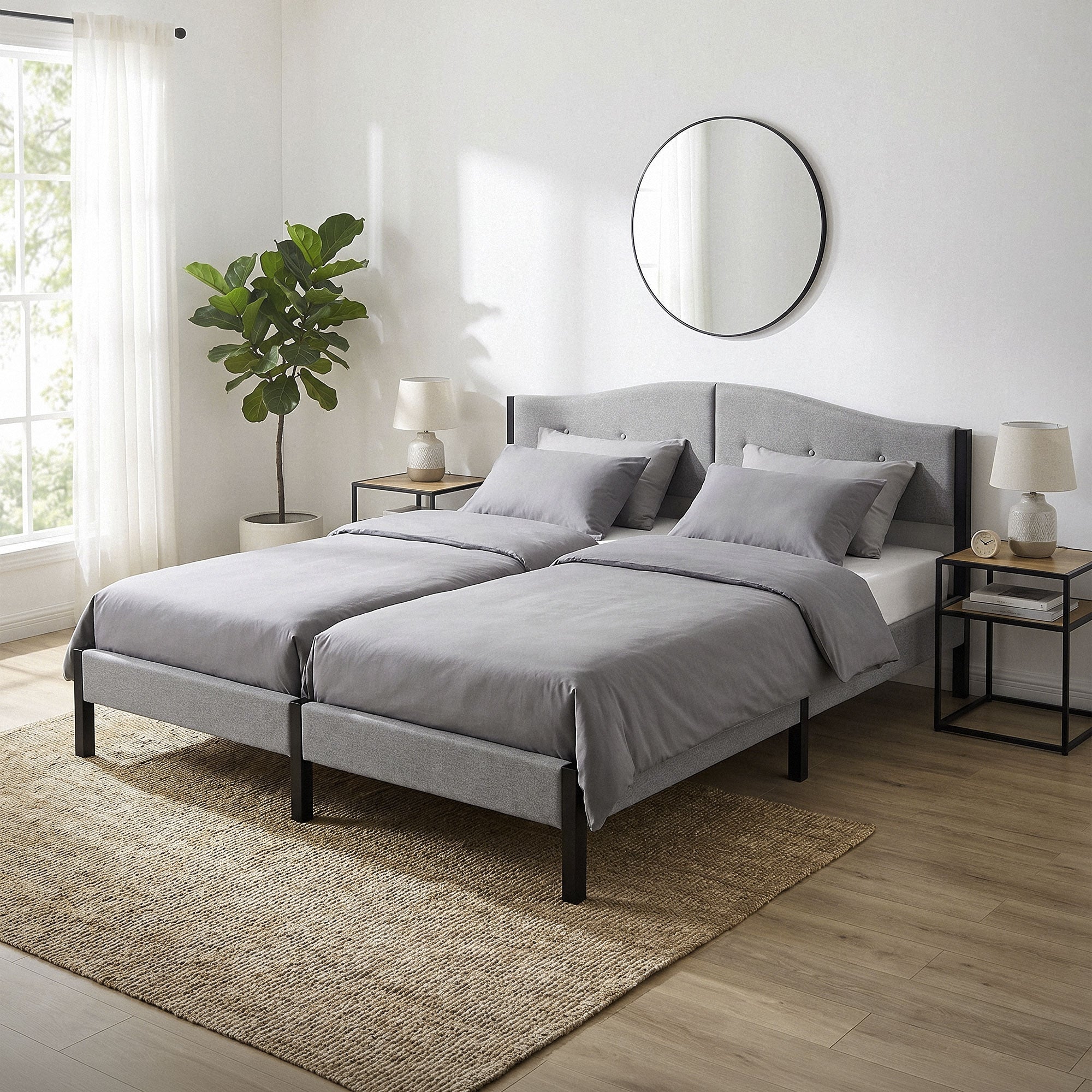 Two single beds with gray bedding and a round wall mirror.