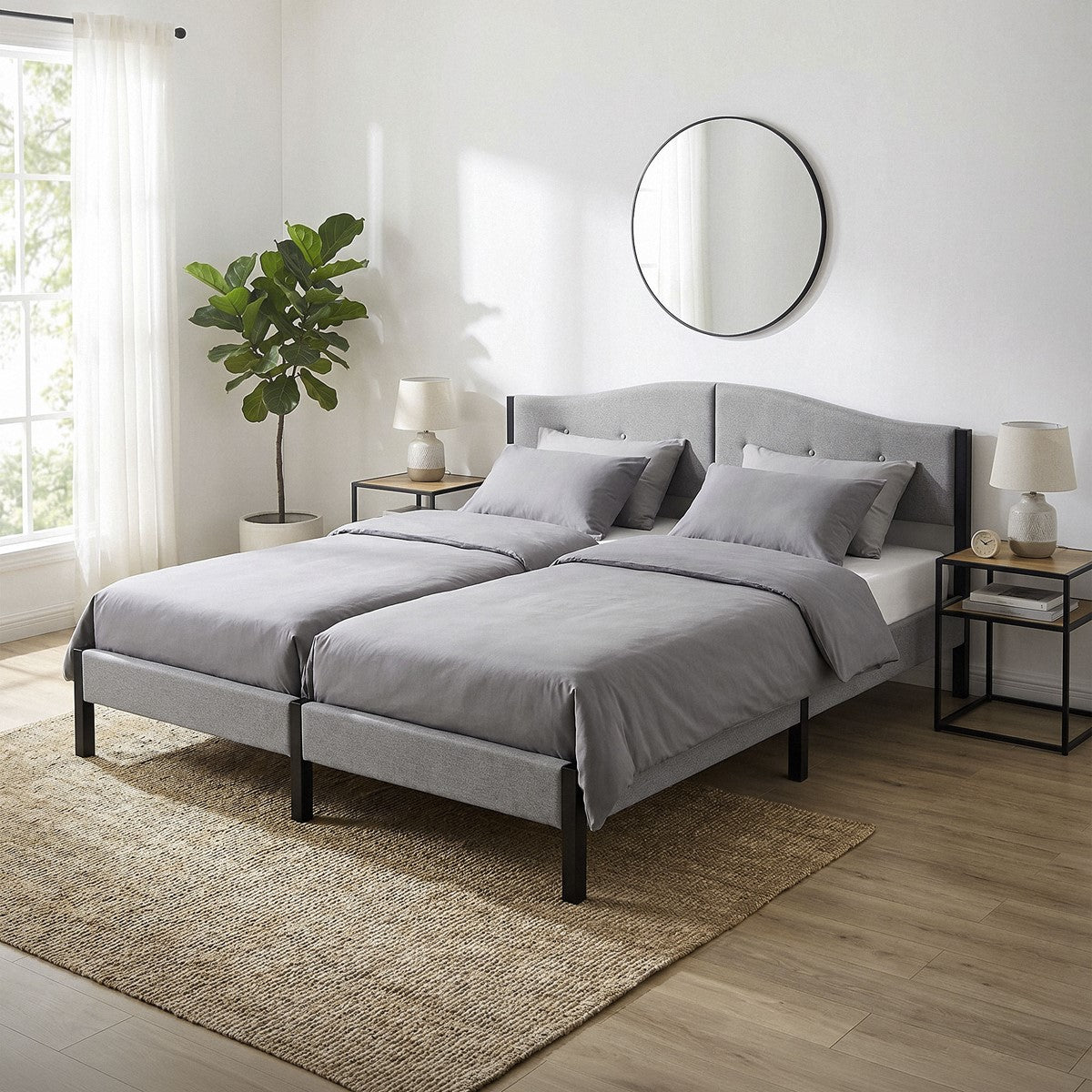 Deux lits simples avec du linge de lit gris et un miroir mural rond.