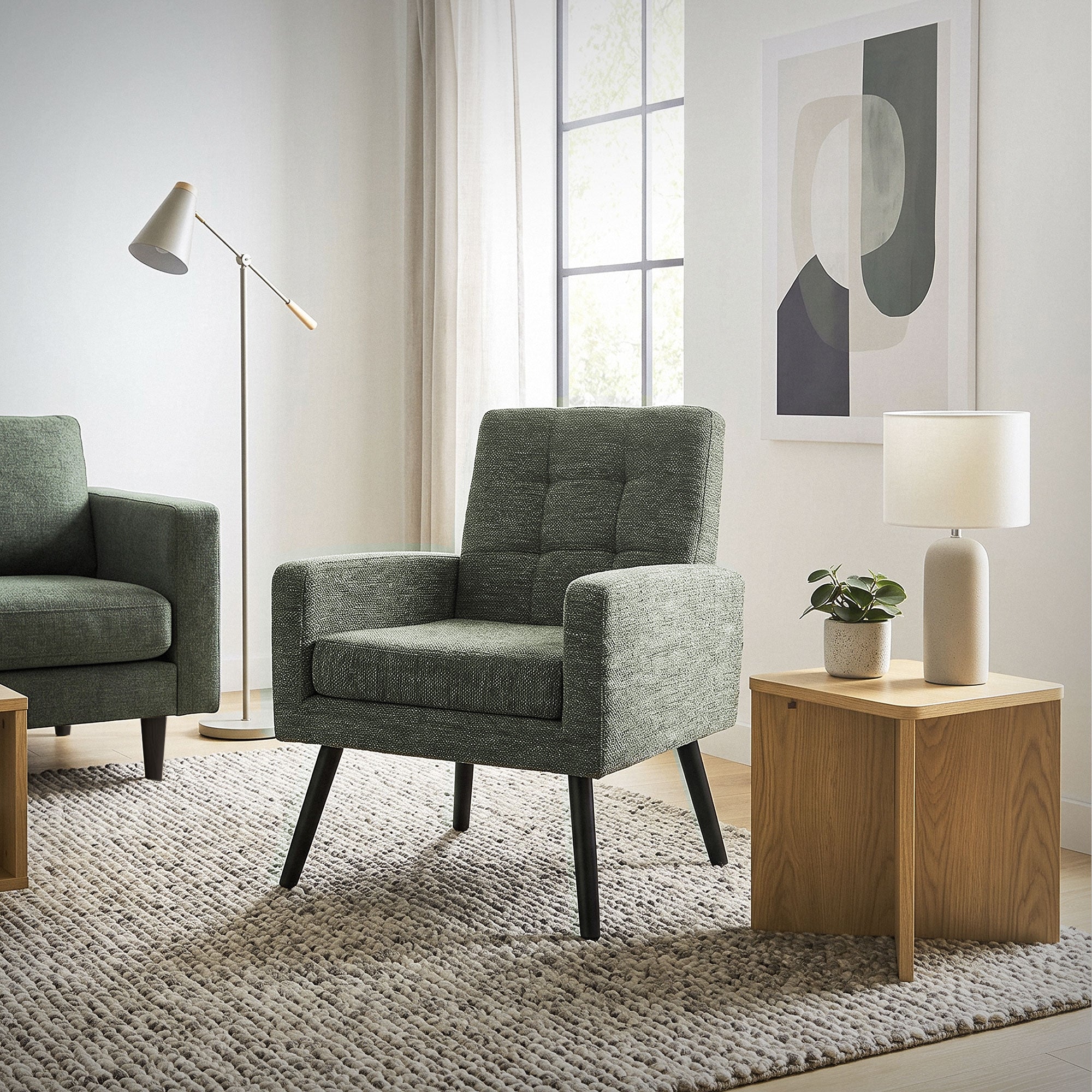 Two gray armchairs in a bright room with a table and lamp.