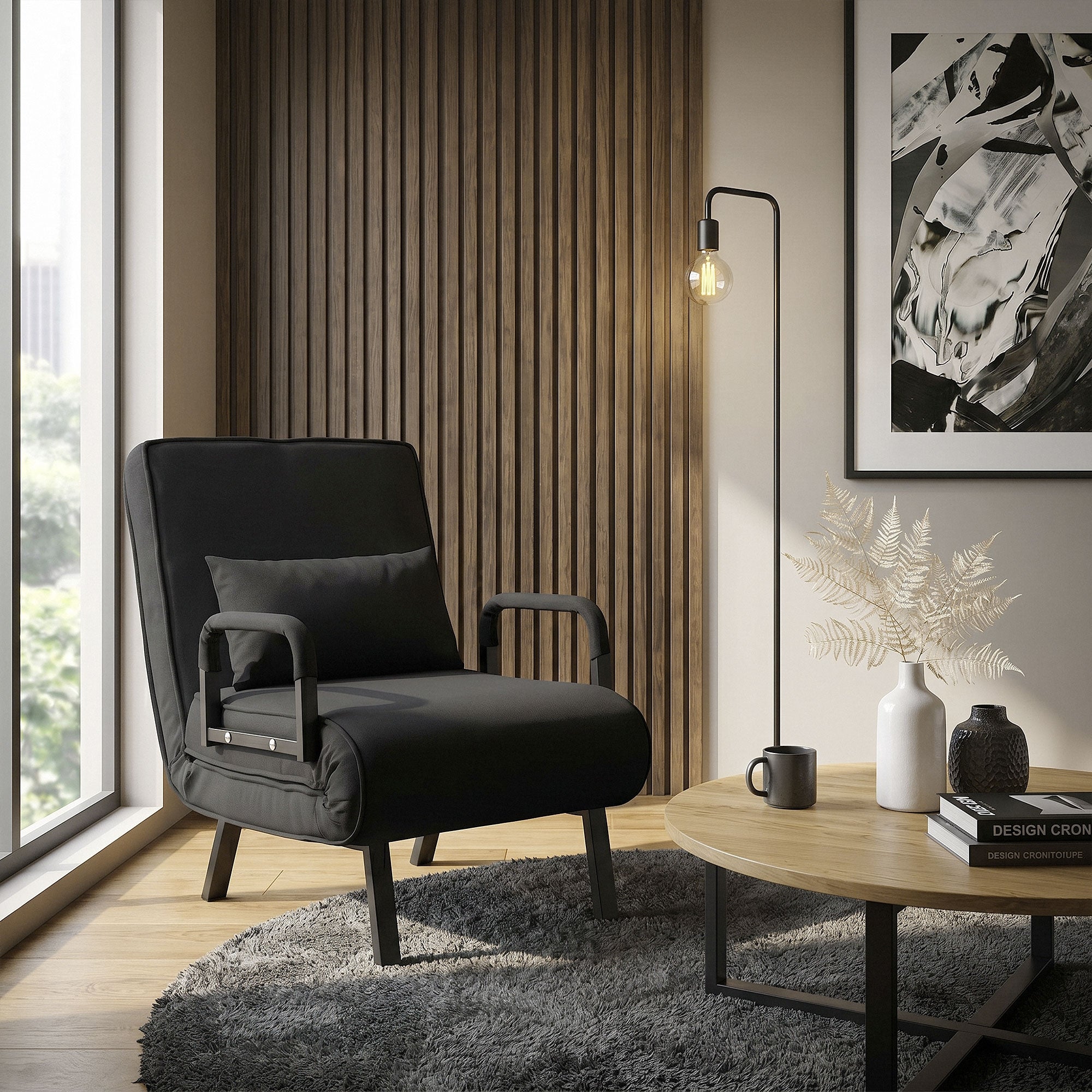 A black armchair with cushions, floor lamp, and table in a modern room.