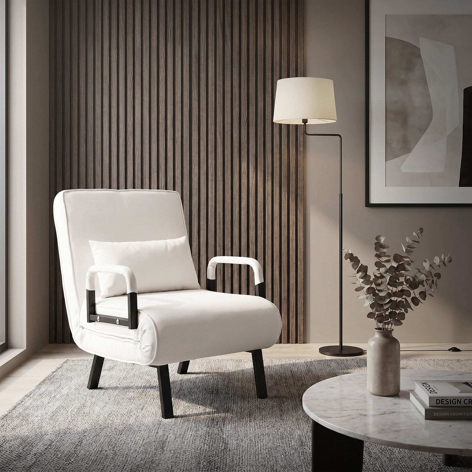 A white armchair with cushions, floor lamp, and table in a modern room.