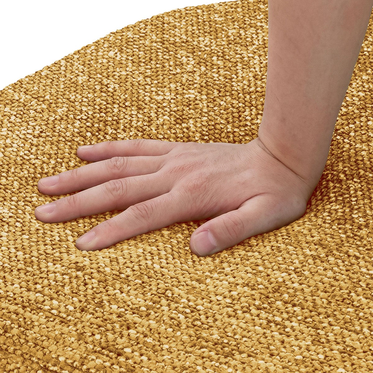 Eine Hand drückt auf einen goldgelben Teppich mit grober Webstruktur.