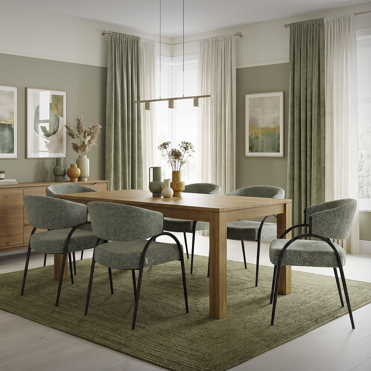 Esszimmer mit Holztisch, sechs graugrünen Stühlen, grünem Teppich und hellen Vorhängen.