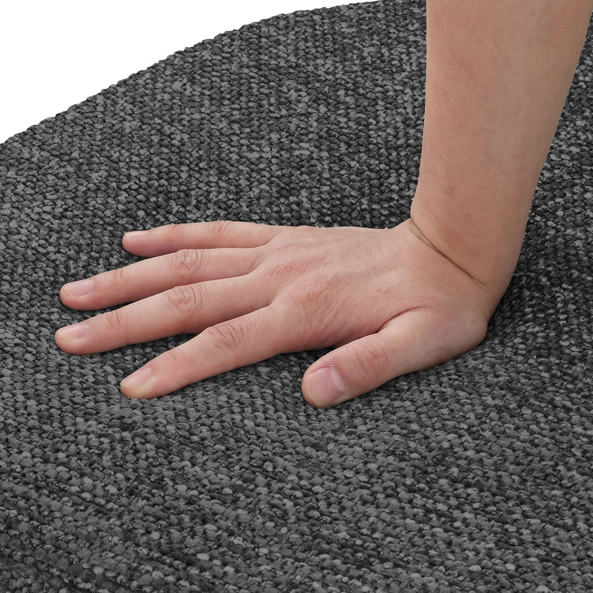 Nahaufnahme einer Hand, die auf grauem, gewebtem Polsterstoff liegt.
