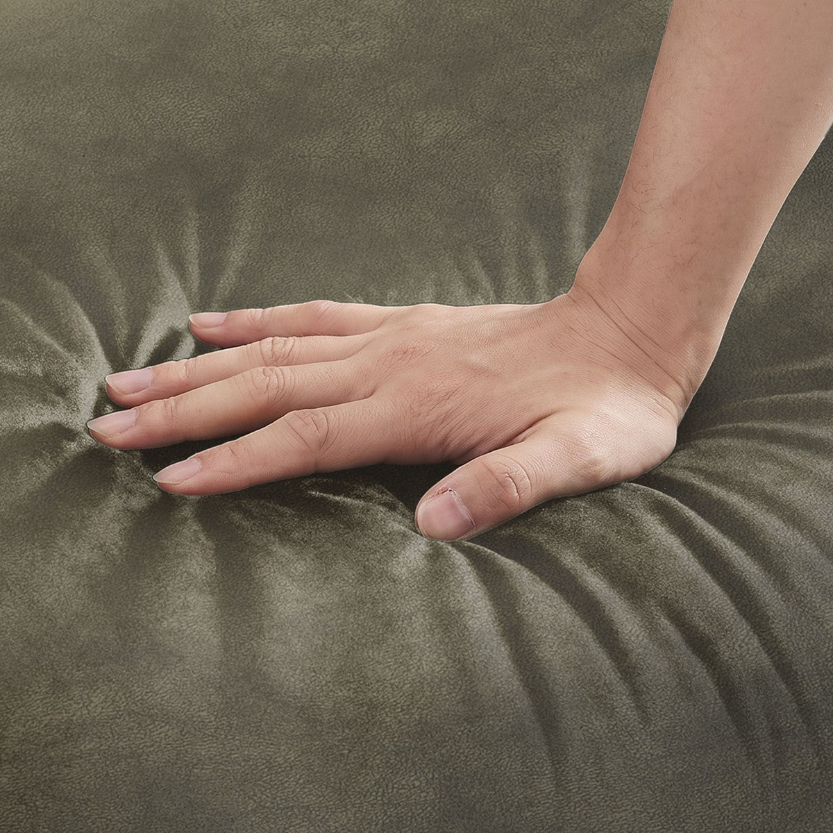 Una mano presiona el cojín de asiento gris oliva de un sillón.