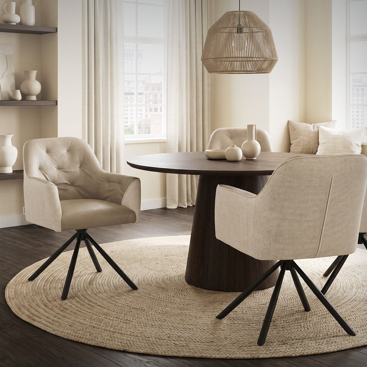 Deux fauteuils rembourrés beiges avec des piètements pivotants noirs se trouvent près d’une table ronde dans une pièce lumineuse.