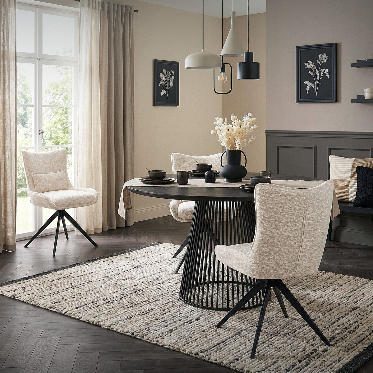 Salle à manger avec des chaises rembourrées couleur crème autour d’une table ronde noire, sur un tapis à motifs.