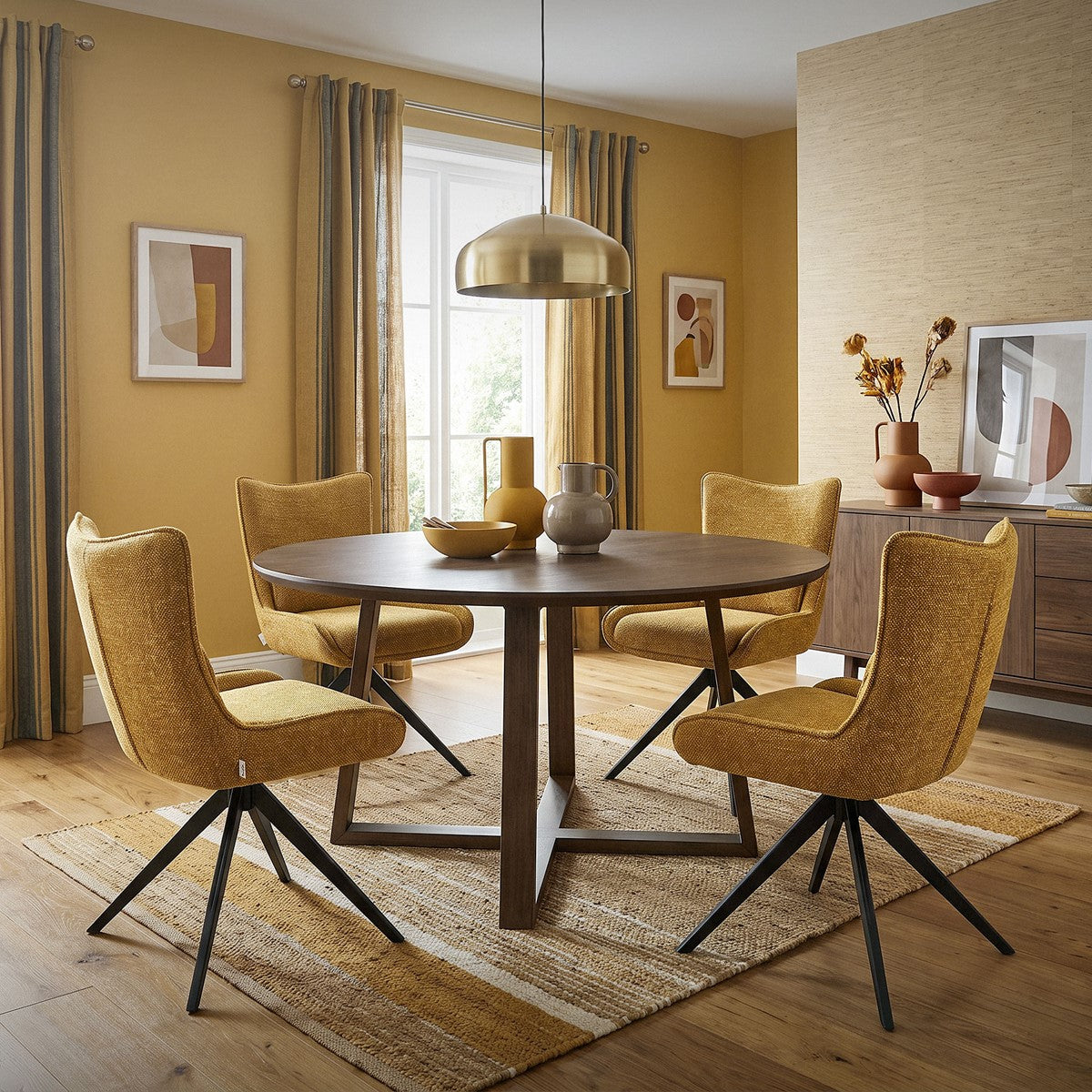Vier senfgelbe Polsterstühle stehen um einen runden Esstisch in einem Esszimmer.