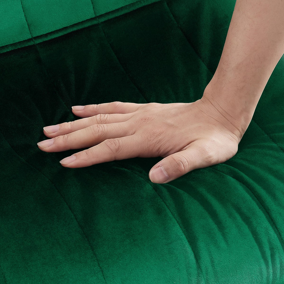 Een hand drukt op de zitting van een donkergroene stoel met fluweelachtige bekleding.