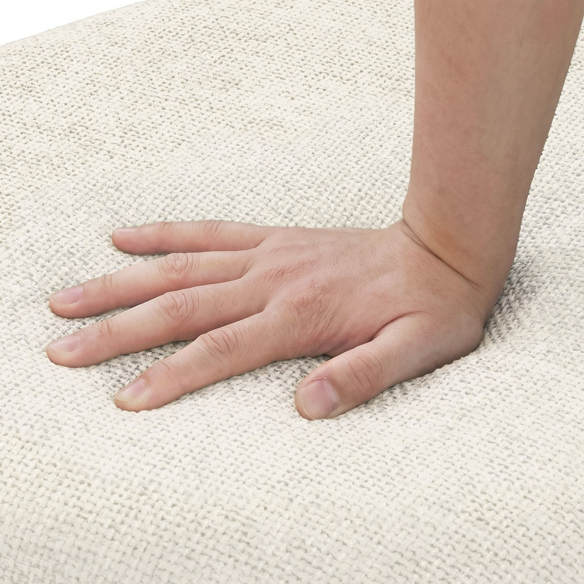 A hand rests on the cream-colored, coarsely woven fabric upholstery of a chair seat.