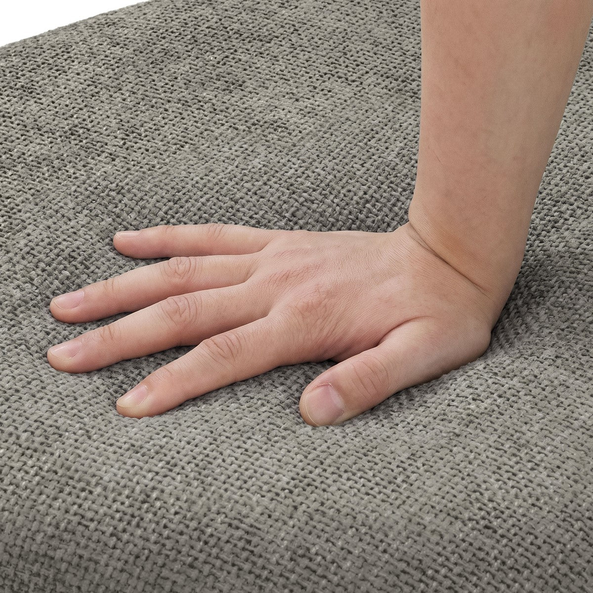 Eine Hand drückt auf den grauen, gewebten Sitzbezug eines Stuhls.