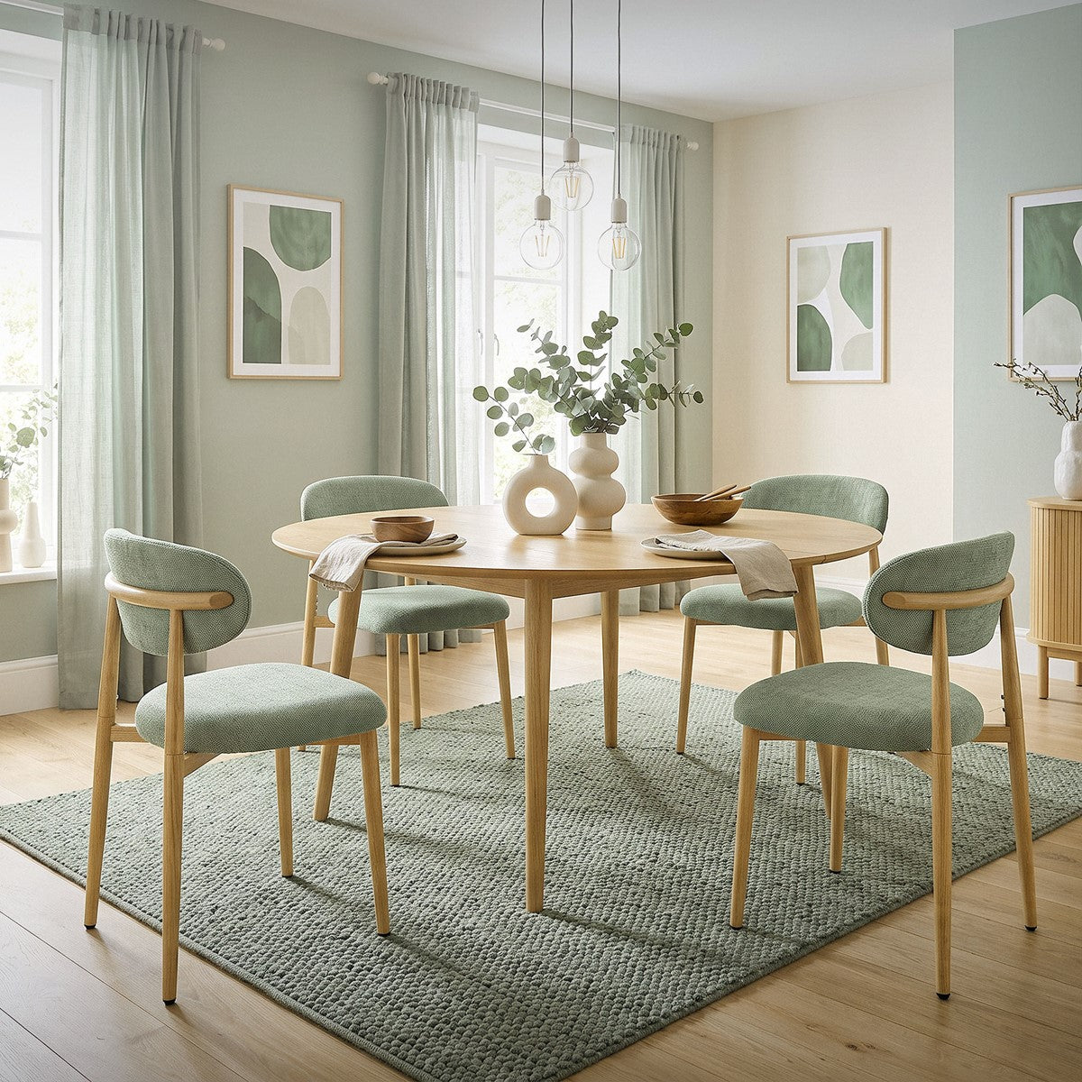 Six beige upholstered dining chairs with wooden legs stand around a round wooden table in a bright dining room.