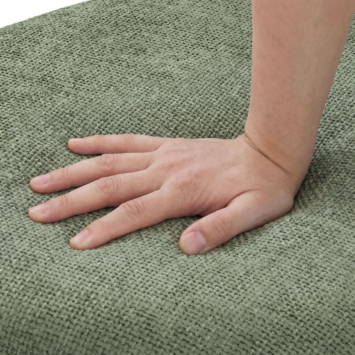 A hand presses on a green woven rug.