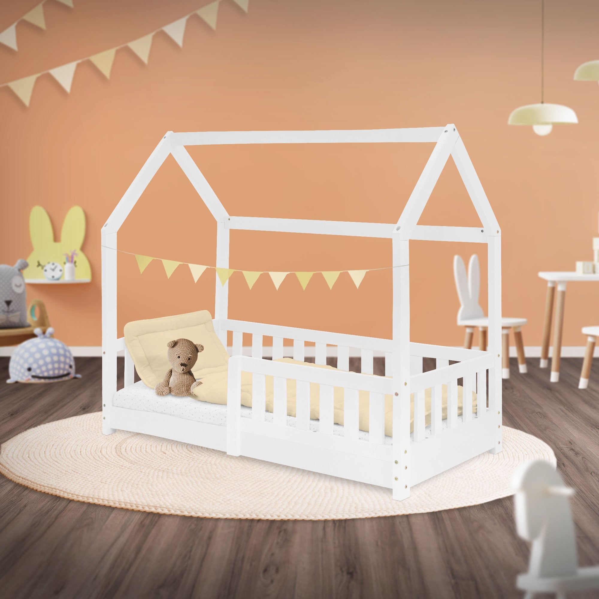 Ein weißes Kinderbett im Raum mit Dekoration und einem Kissen.