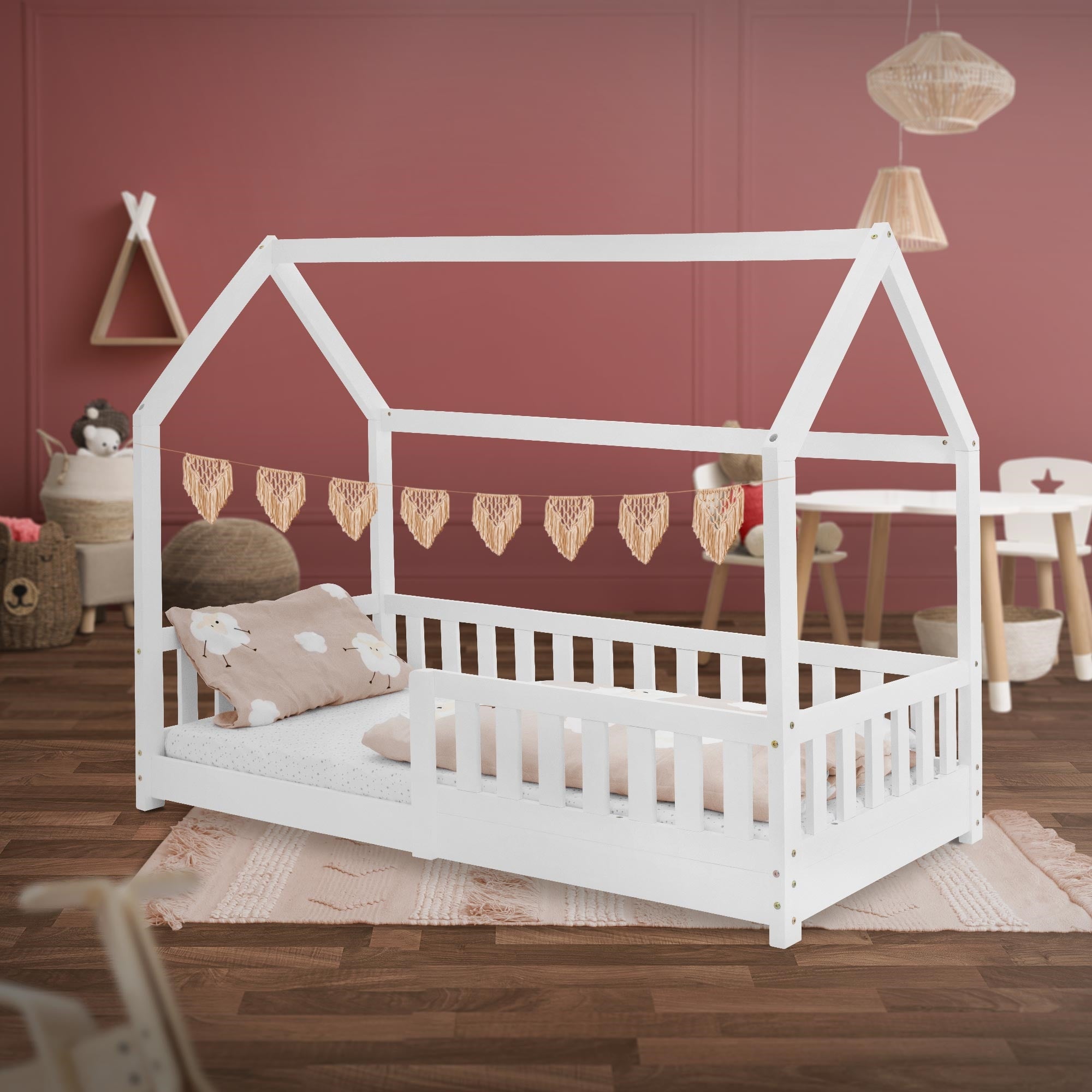 Letto per bambini bianco con cuscino e coperta, decorato con ghirlanda a forma di cuore.