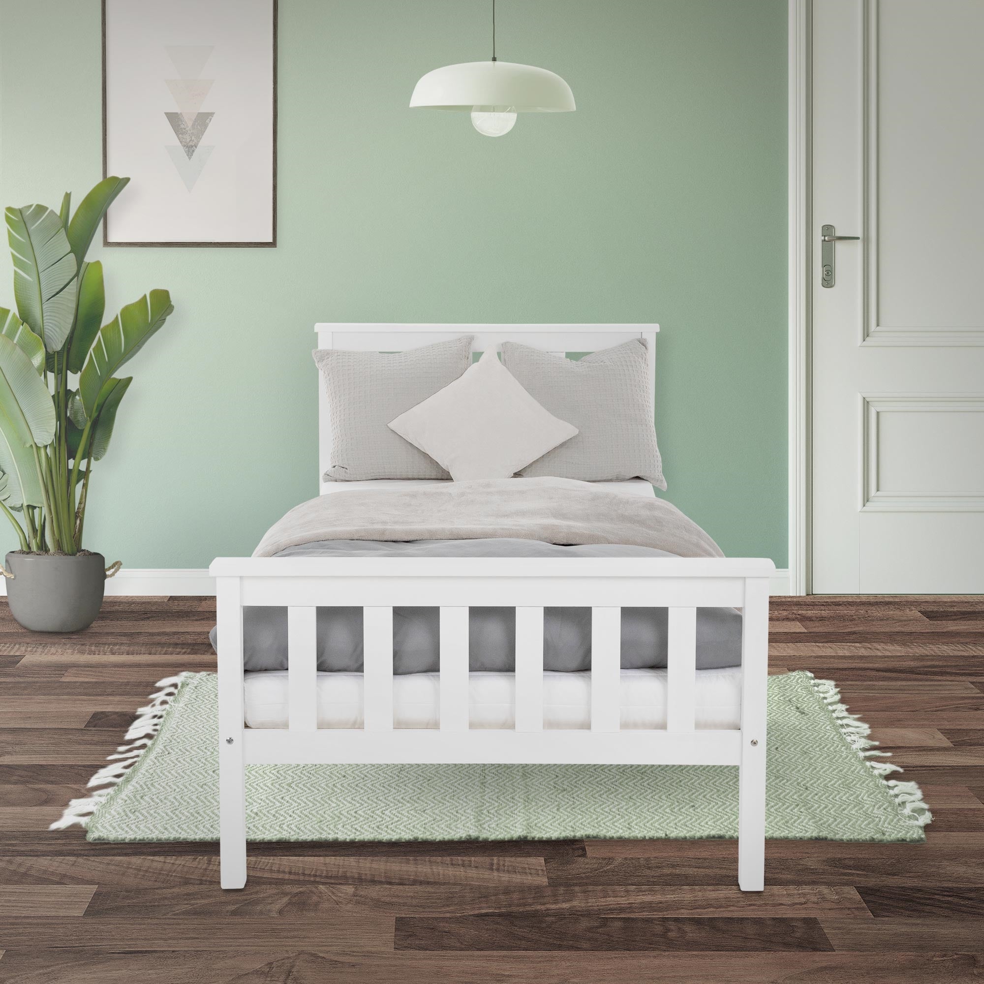 Cama blanca en una habitación con pared verde y plantas.