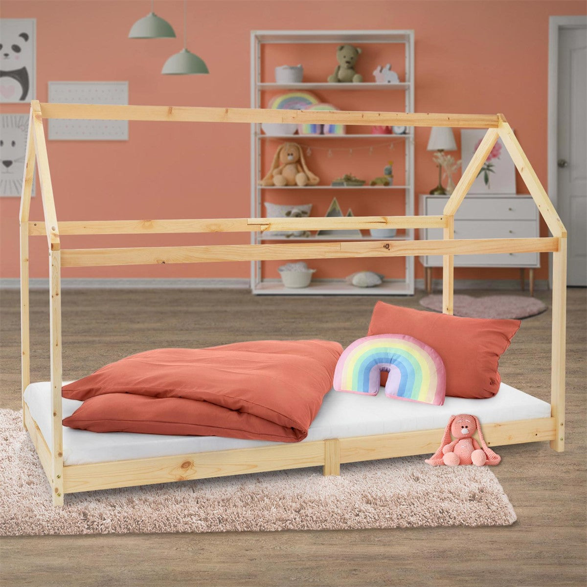 Un lit pour enfant en forme de maison avec un coussin et une couverture arc-en-ciel.