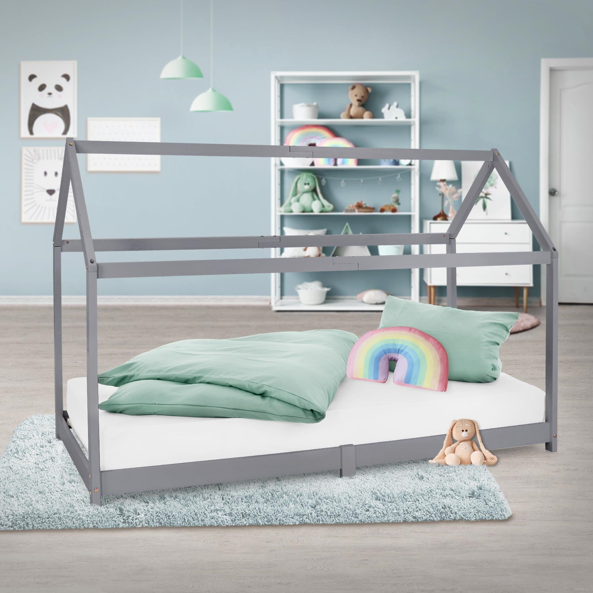 Bed met kussen en deken in een lichte kamer met speelgoedrek.