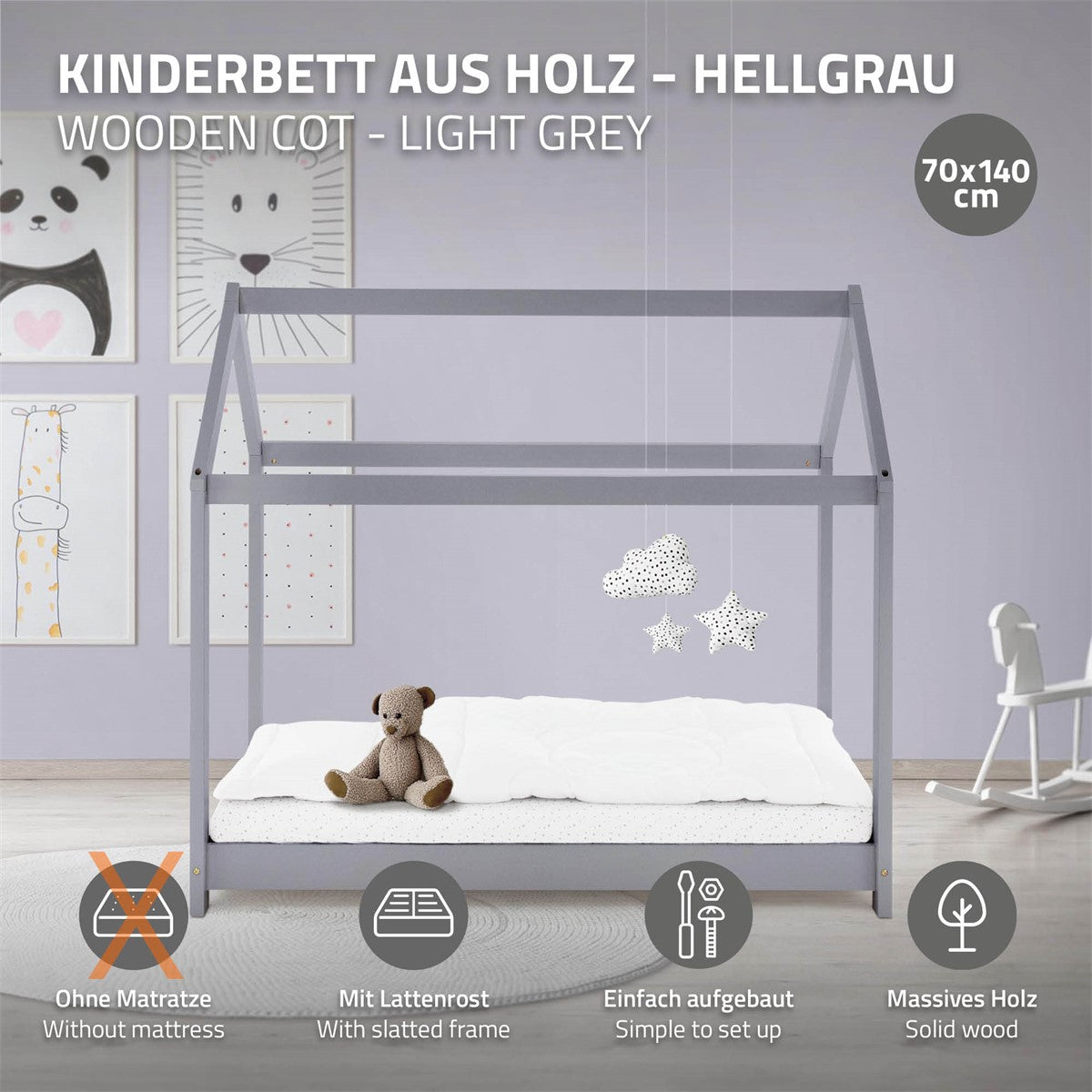 Letto per bambini in legno grigio chiaro con materasso e giocattoli, accanto a una parete con quadri.