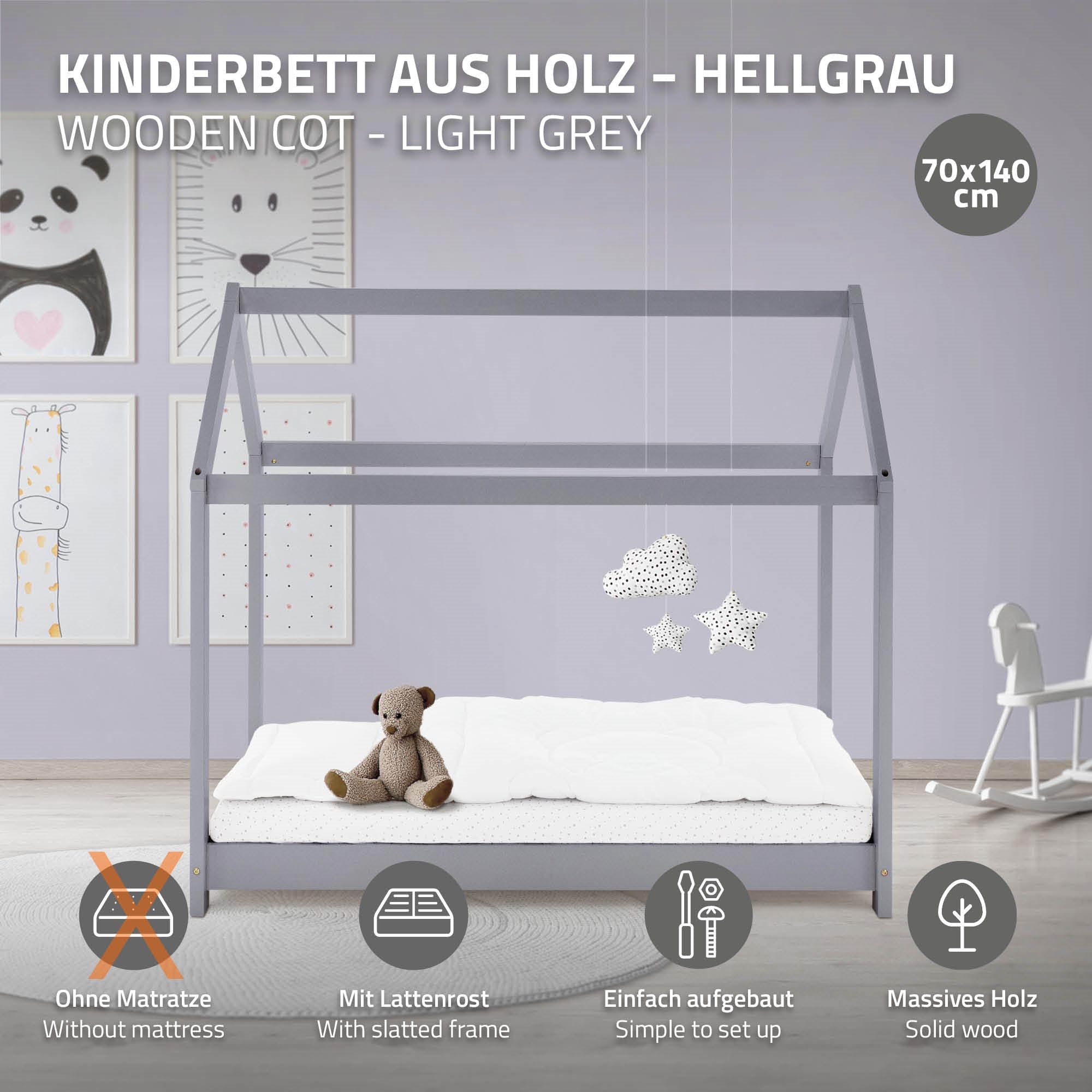 Hellgraues Holz-Kinderbett mit Matratze und Spielzeug, an einer Wand mit Bildern.