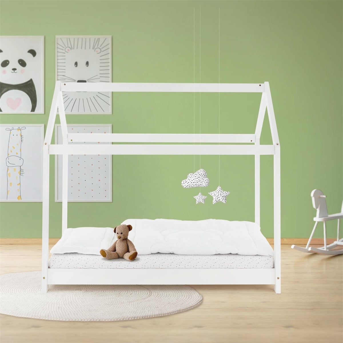Letto a casetta bianco con materasso e orsacchiotto davanti a una parete verde.