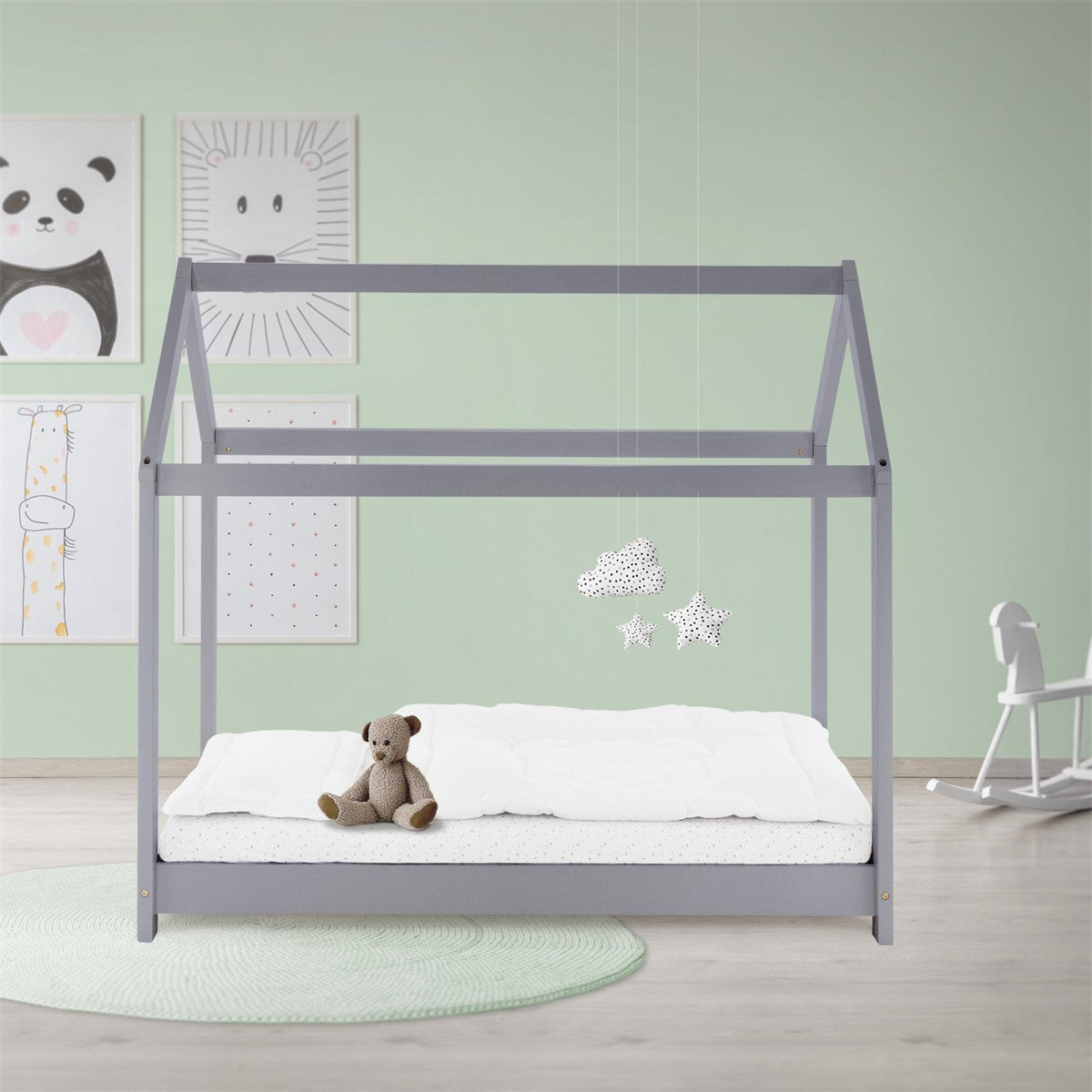 Gray house bed with a white mattress and teddy bear in a children's room with a mint green wall.