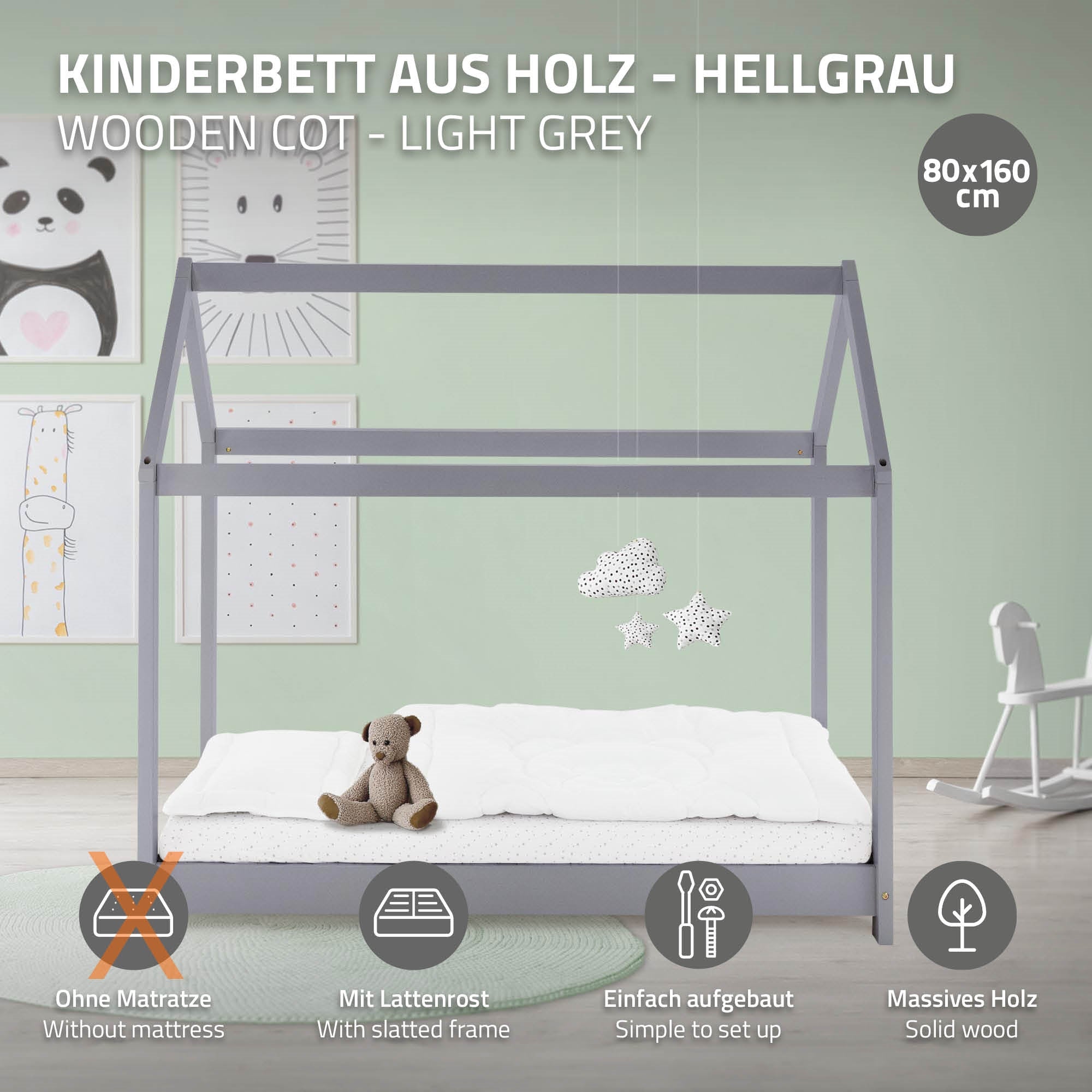 Fából készült gyerekágy világosszürkében egy mackóval és csillagfüggőkkel.