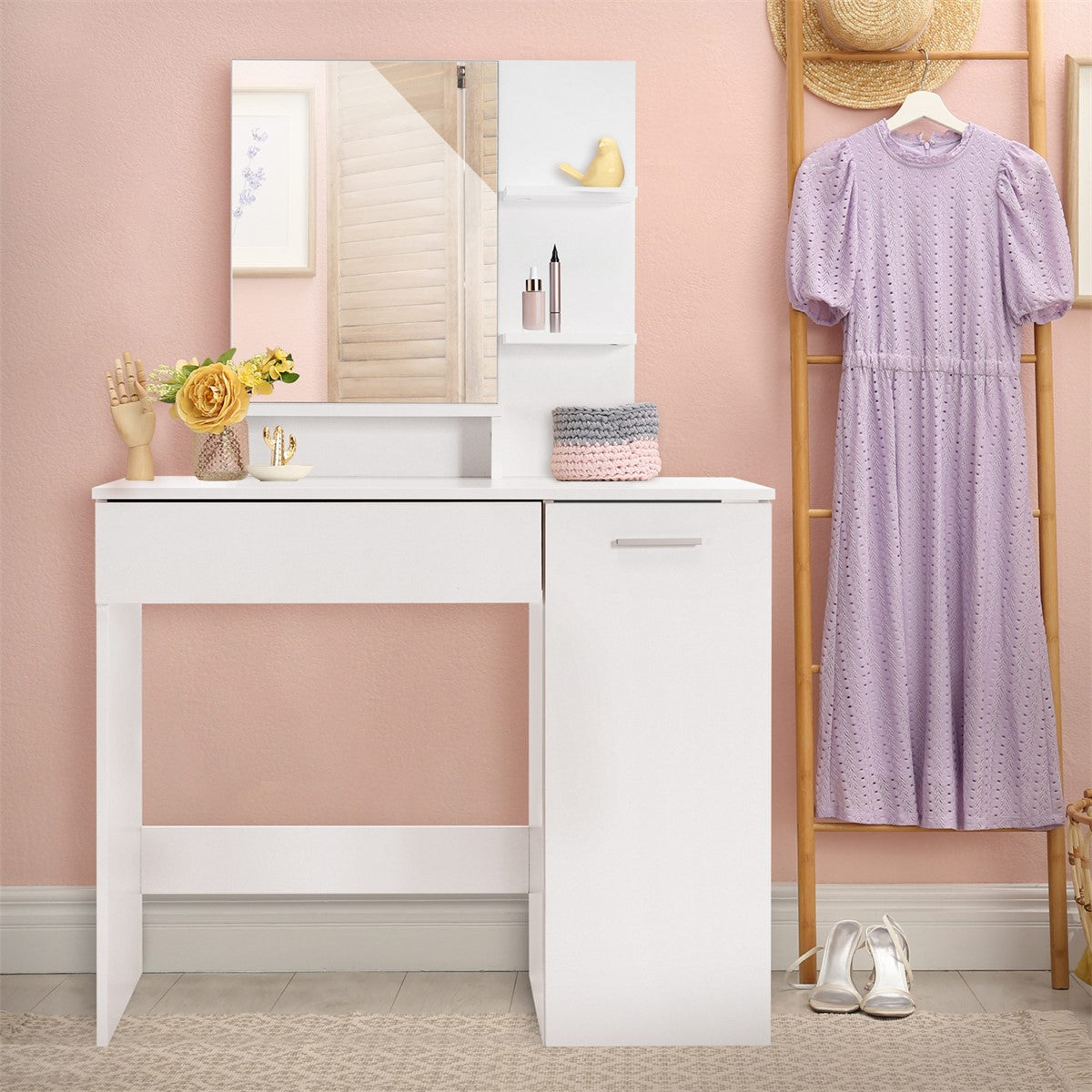 A white dressing table with a mirror, flowers, and a purple dress on the wall.