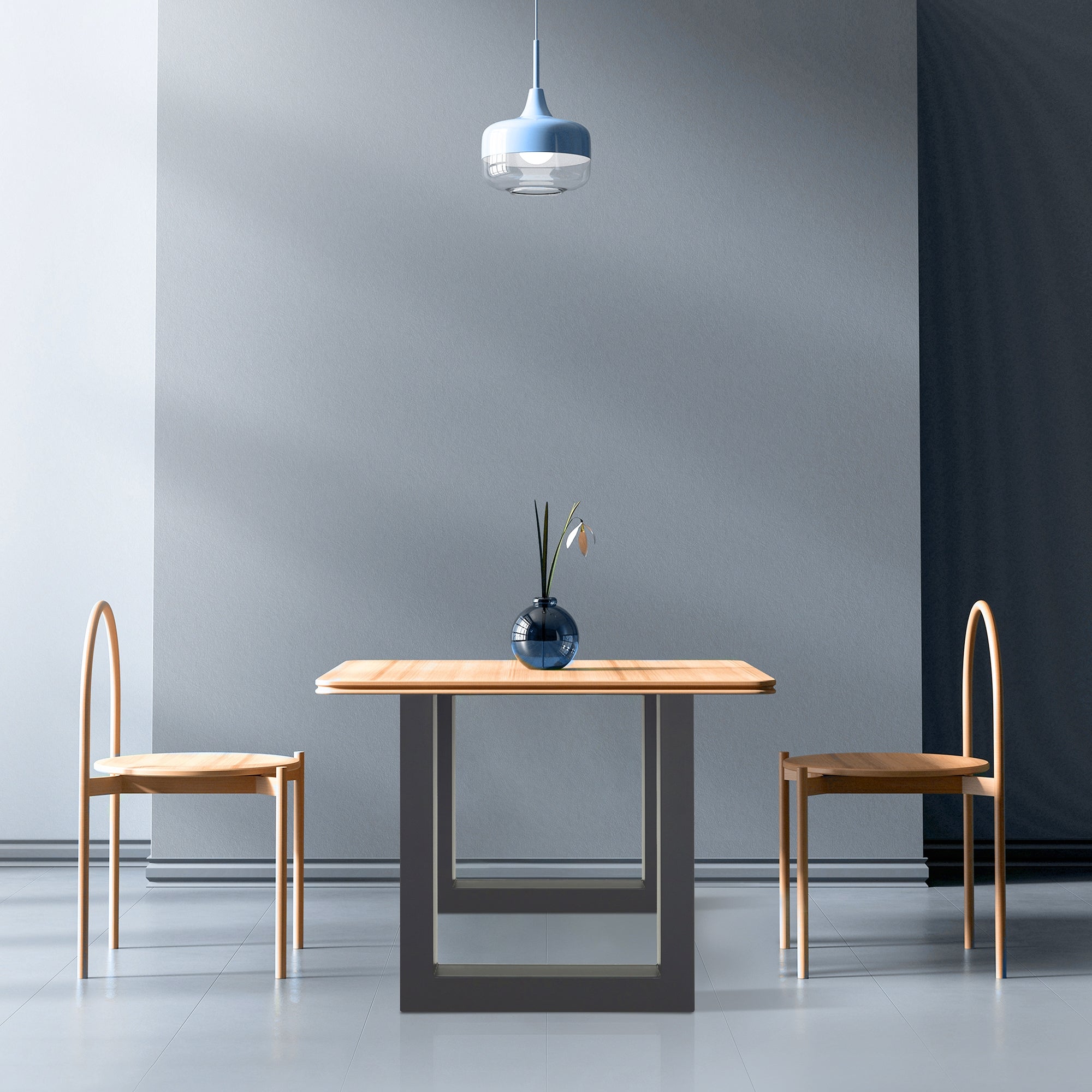 Ein Tisch mit zwei Stühlen in einem Raum mit grauen Wänden und einer blauen Lampe.