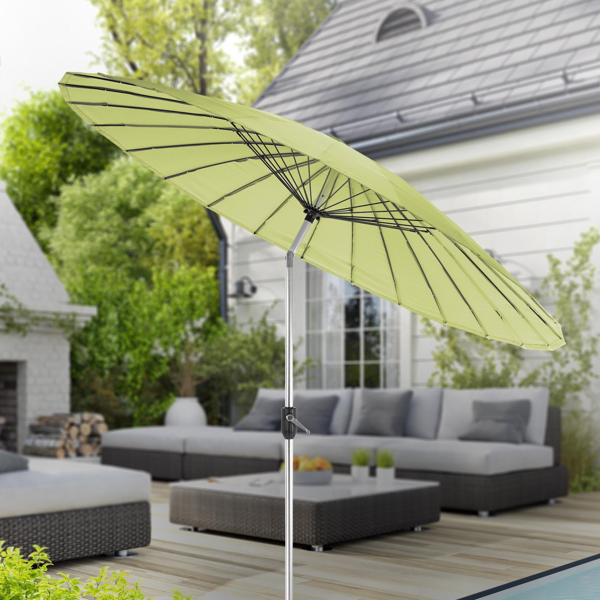 Ombrellone verde su una terrazza con mobili da giardino sullo sfondo.